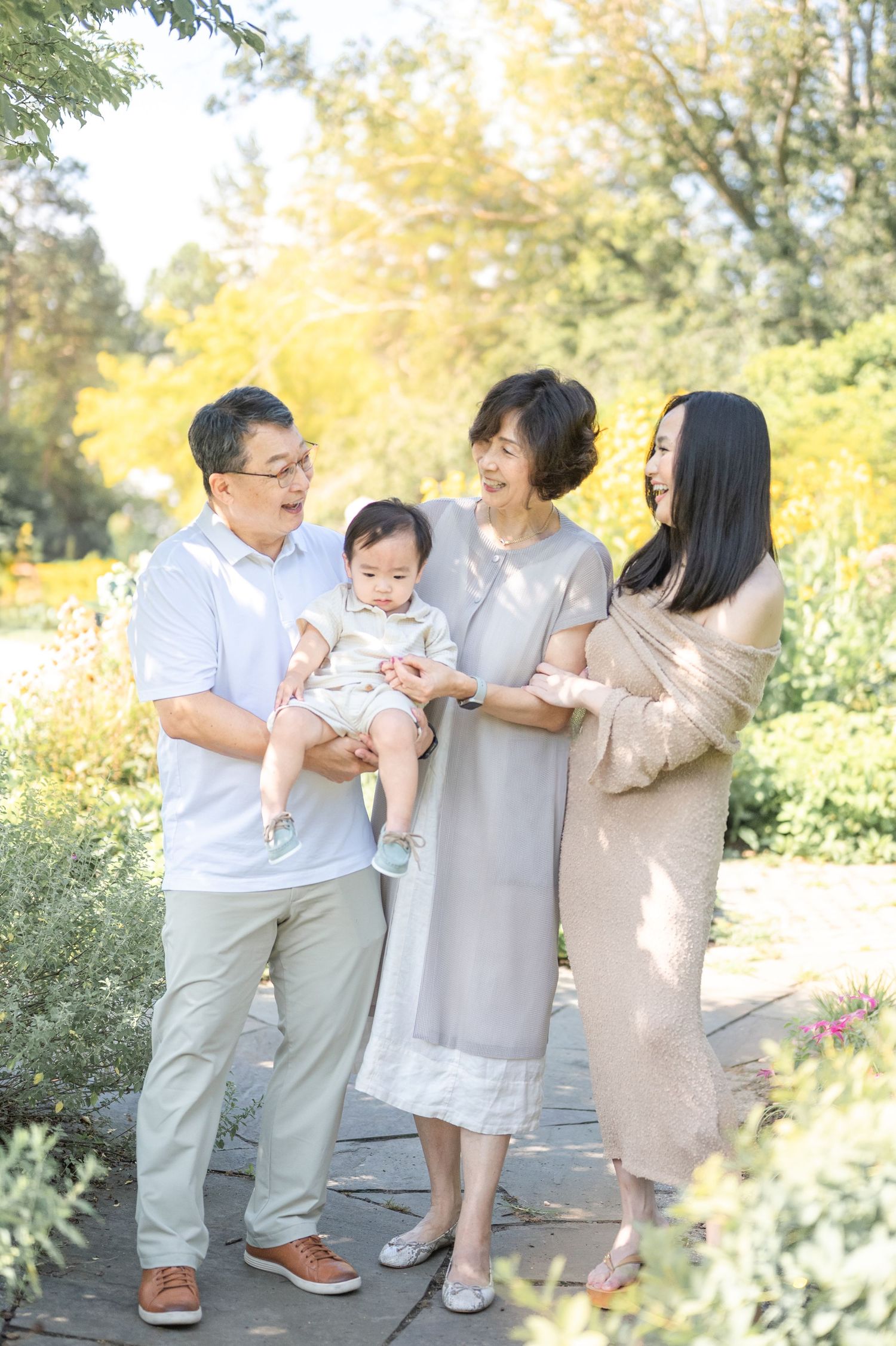 A family in light, neutral-colored clothing plays together outdoors during autumn, creating joyful candid moments. Arlington photographer
