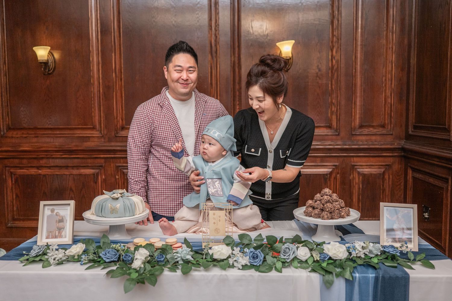 A couple cuts into a decorative cake at an elegant table with floral arrangements and dessert displays. Dohl