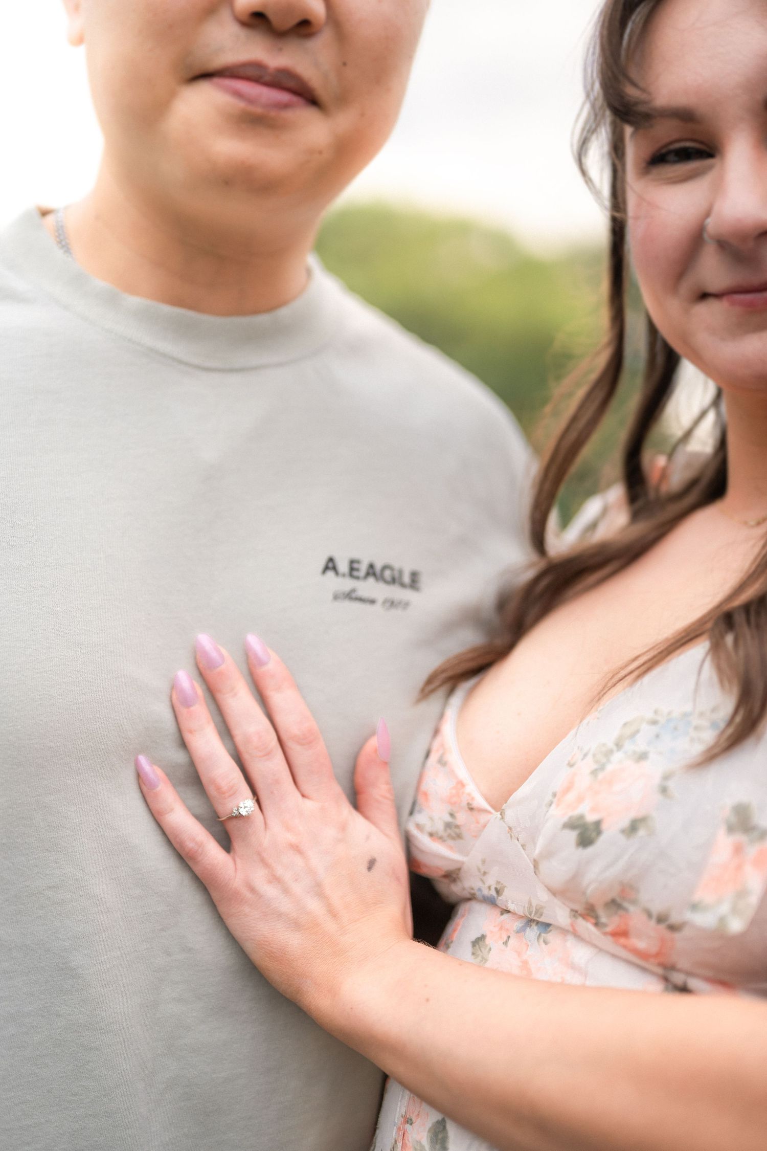 Close-up view showing a couple embracing with focus on an engagement ring and casual attire. Leesburg Family Photographer Taylor Swift