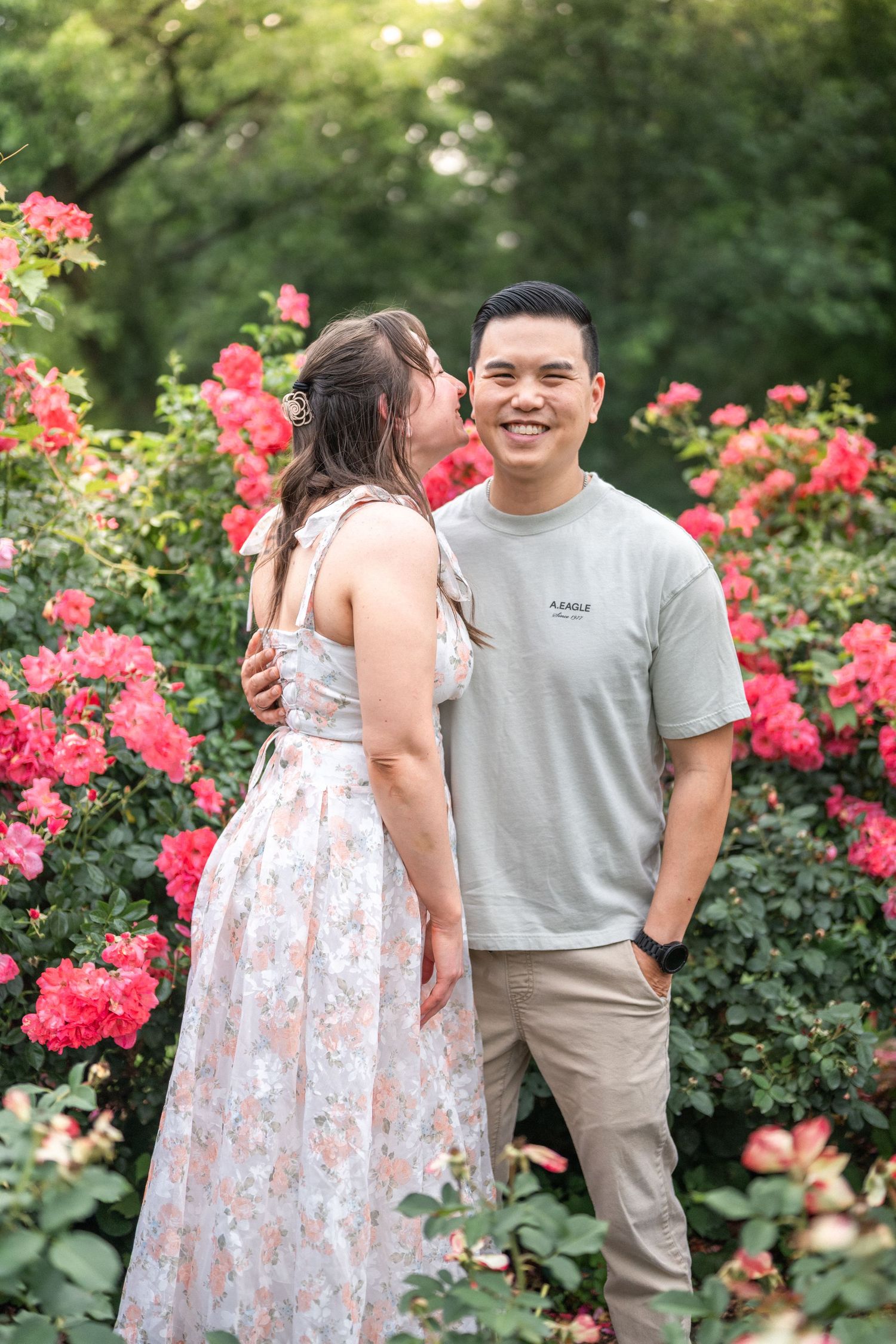 A couple sharing romantic moments in a garden with blooming pink roses on a sunny summer day. engagement Taylor Swift Travis Kelce