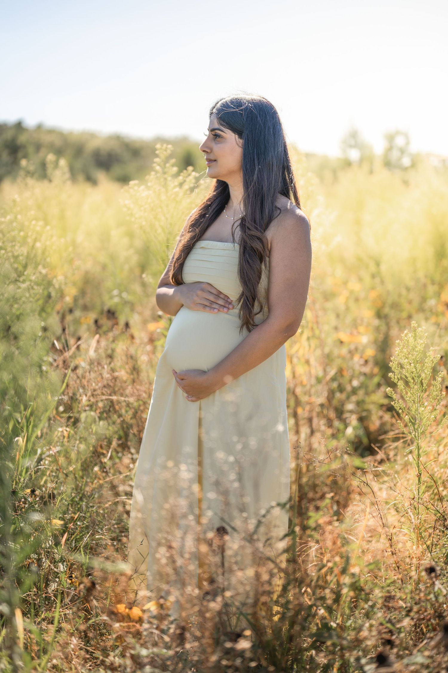 Maternity photo series showing expectant mother cradling belly in golden sunlit field with wildflowers at sunset.