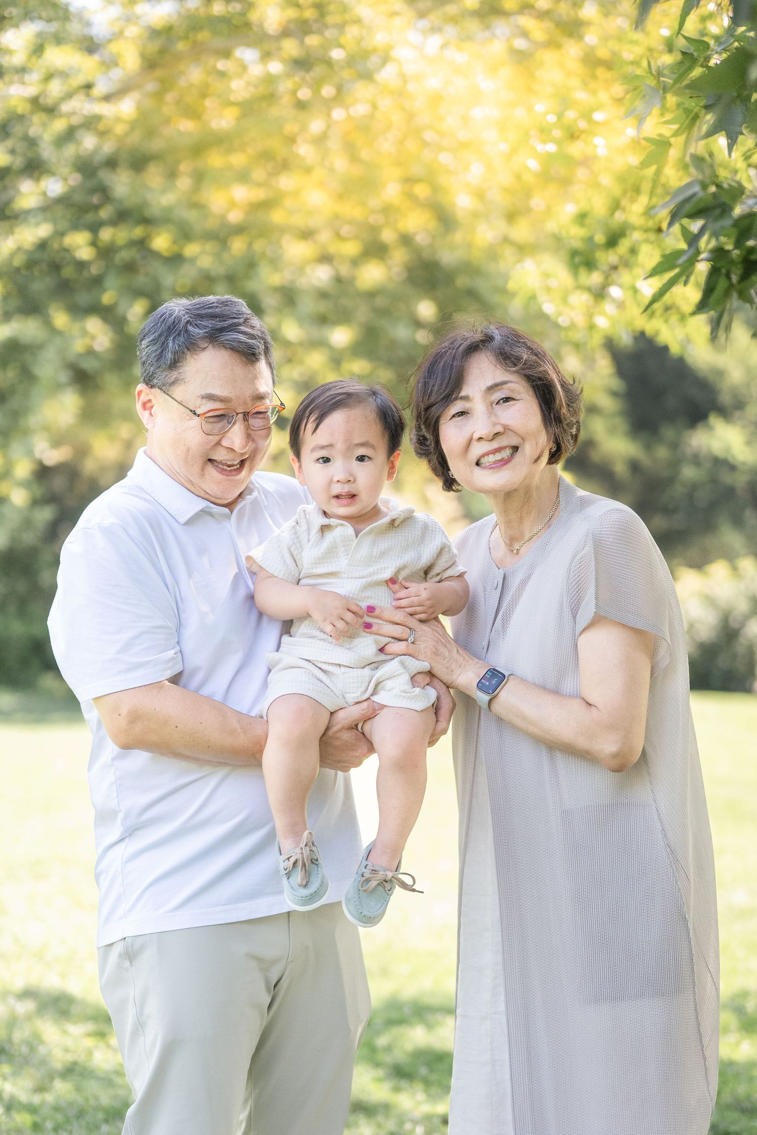 Family enjoying a playful moment together in a sunlit park during a golden hour photoshoot.