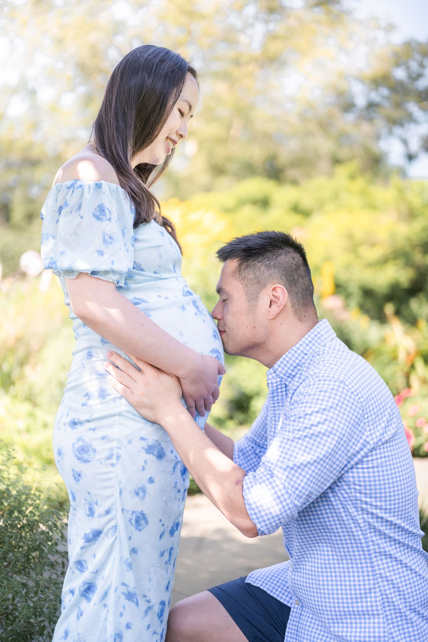 A tender moment is captured between a couple in flowy blue and white outfits against a soft natural outdoor setting. Alexandria photographer