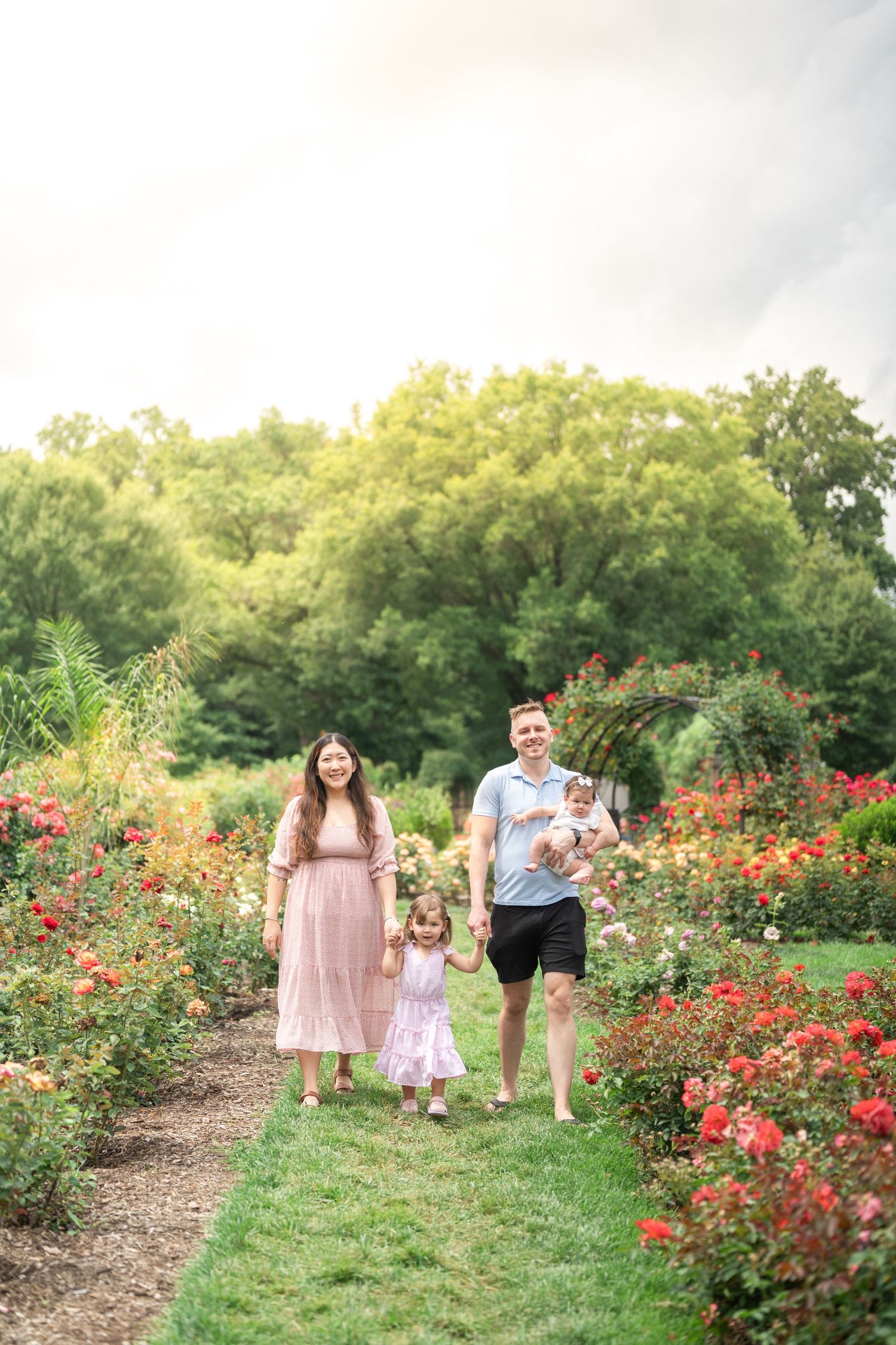 Family walks together through colorful garden path with roses. Northern Virginia Family Photographer