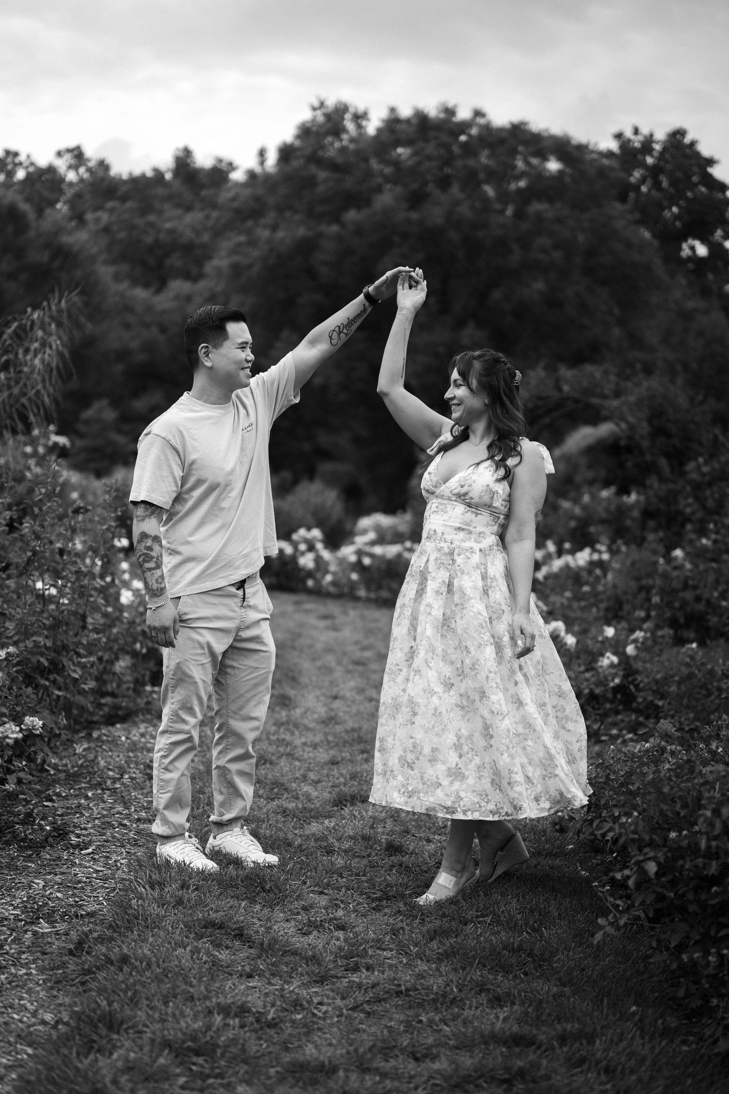 A couple dancing and twirling together in a garden setting captured in black and white. Northern Virginia Family Photographer