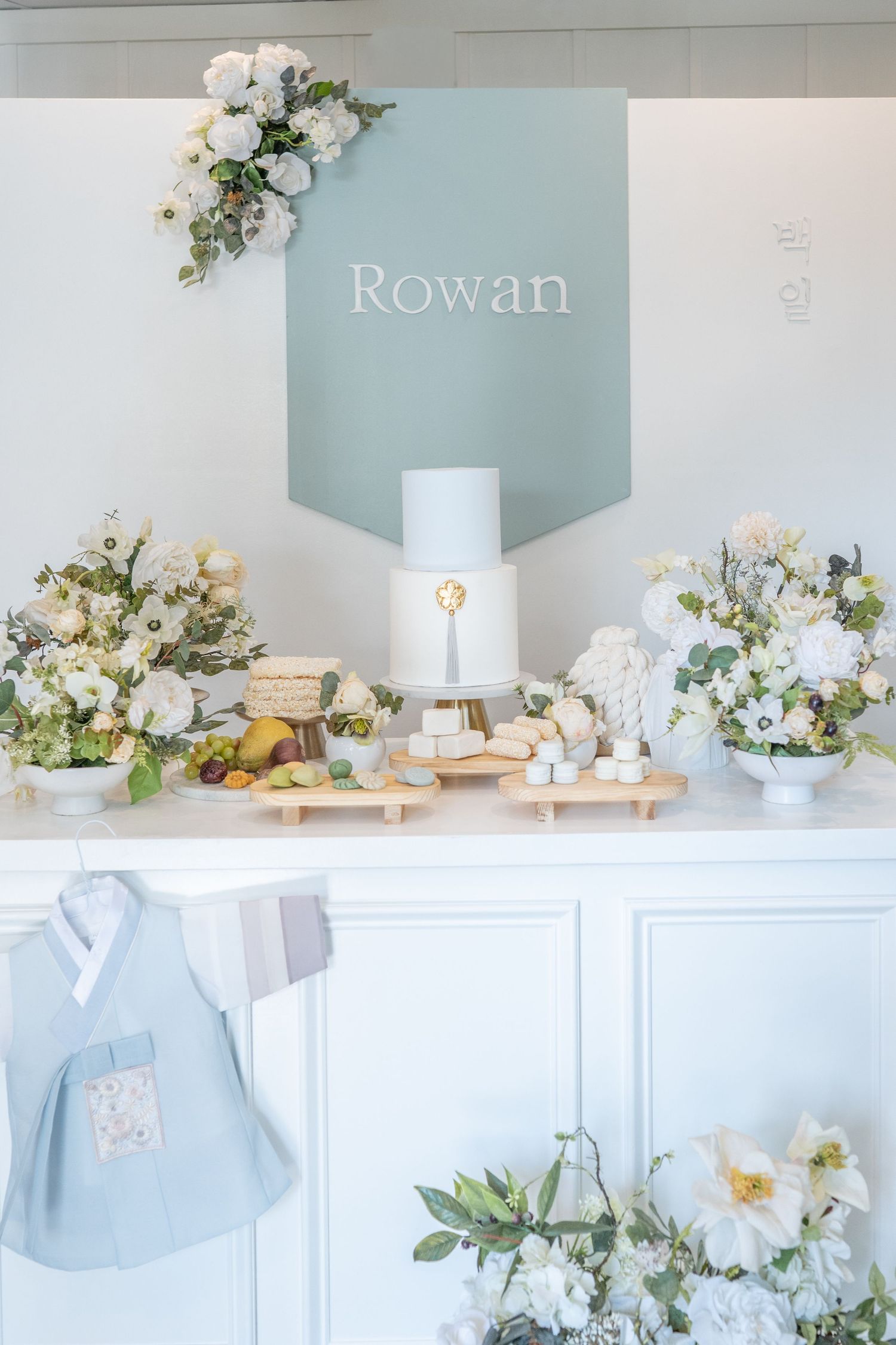 An elegant baby shower setup in soft blue and white with delicate floral arrangements and textured decor elements.