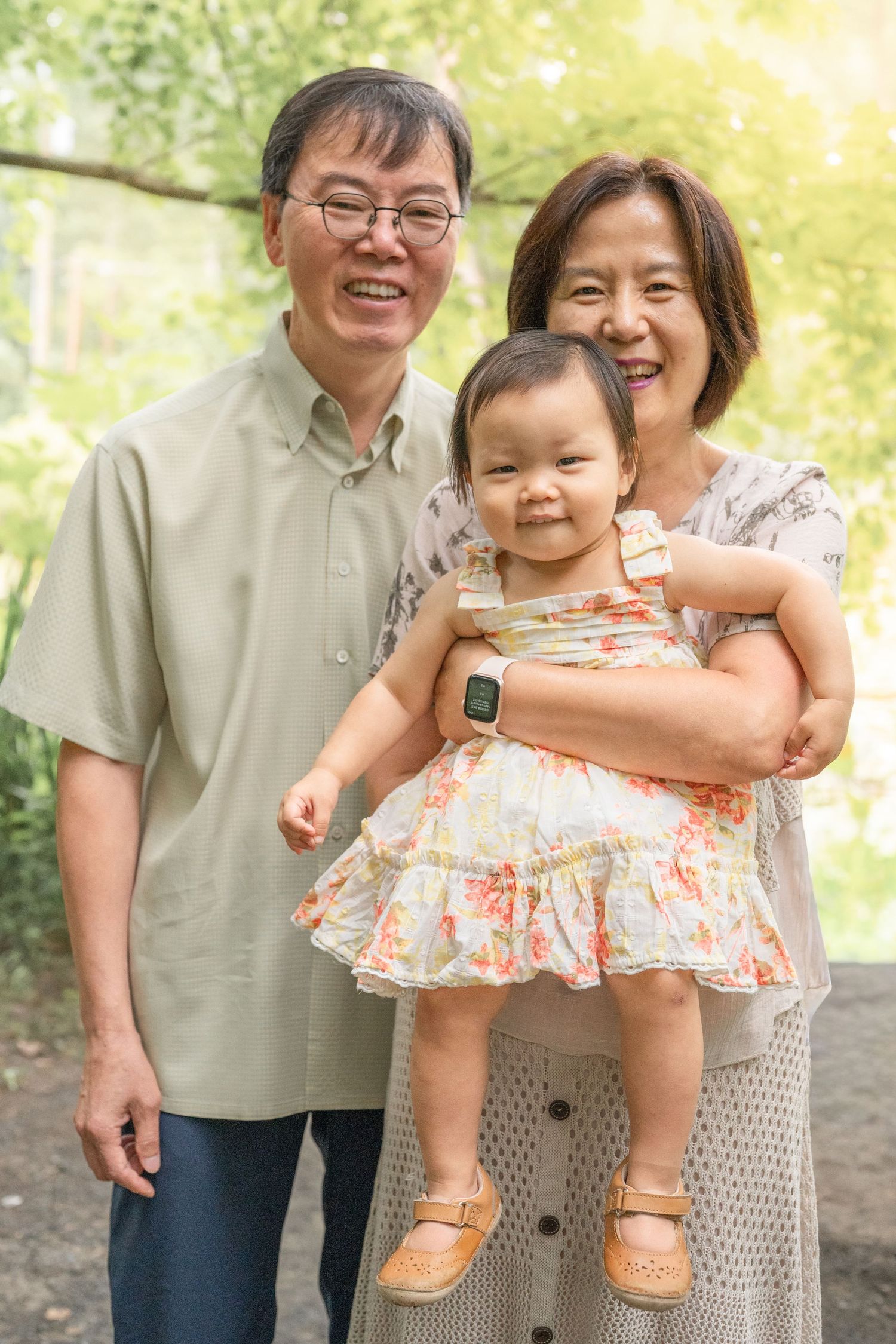 A joyful family portrait series in an outdoor setting with warm sunlight filtering through trees.