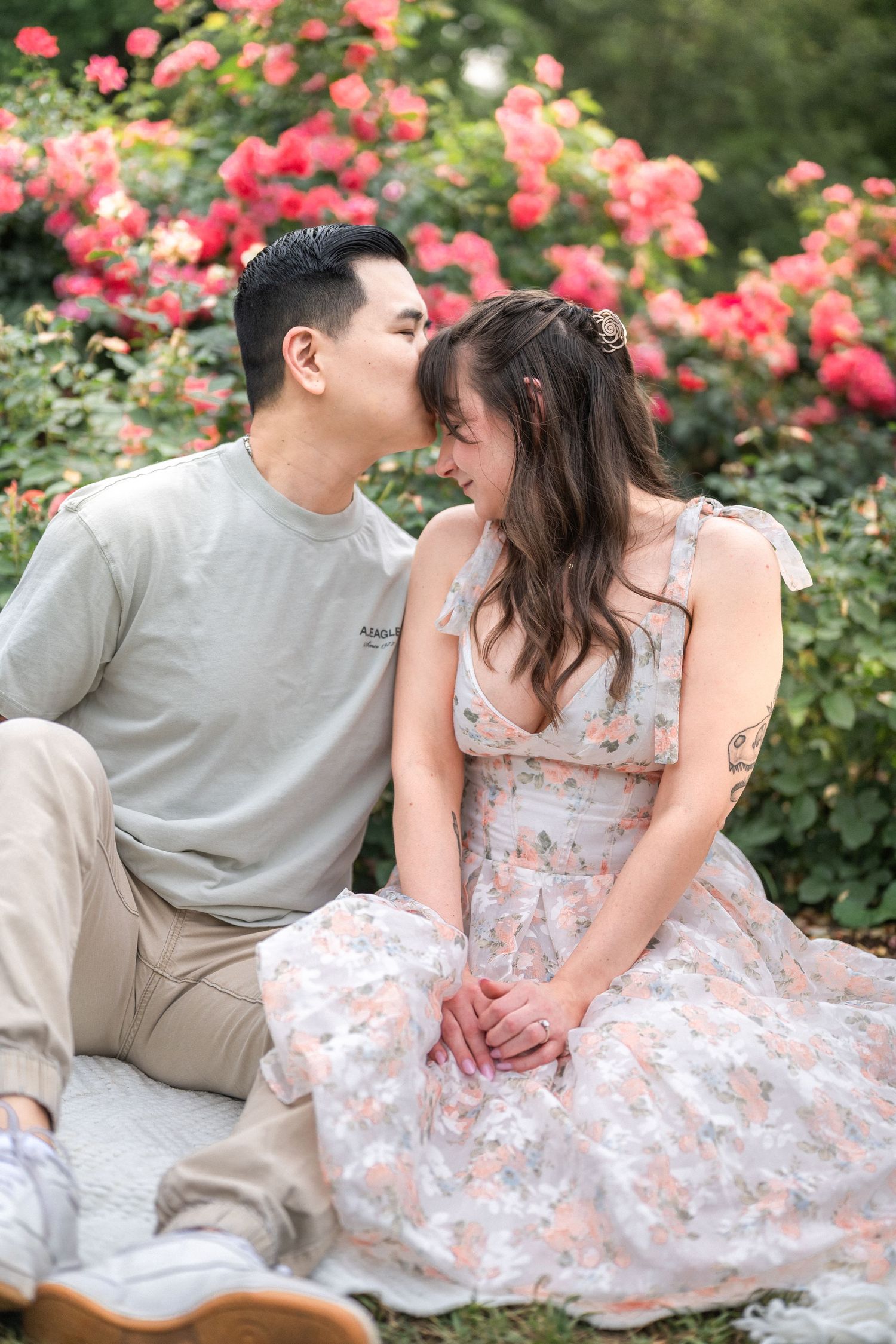 An intimate moment between a couple sitting among pink rose bushes in a garden setting. Northern Virginia Family Photographer Taylor Swift