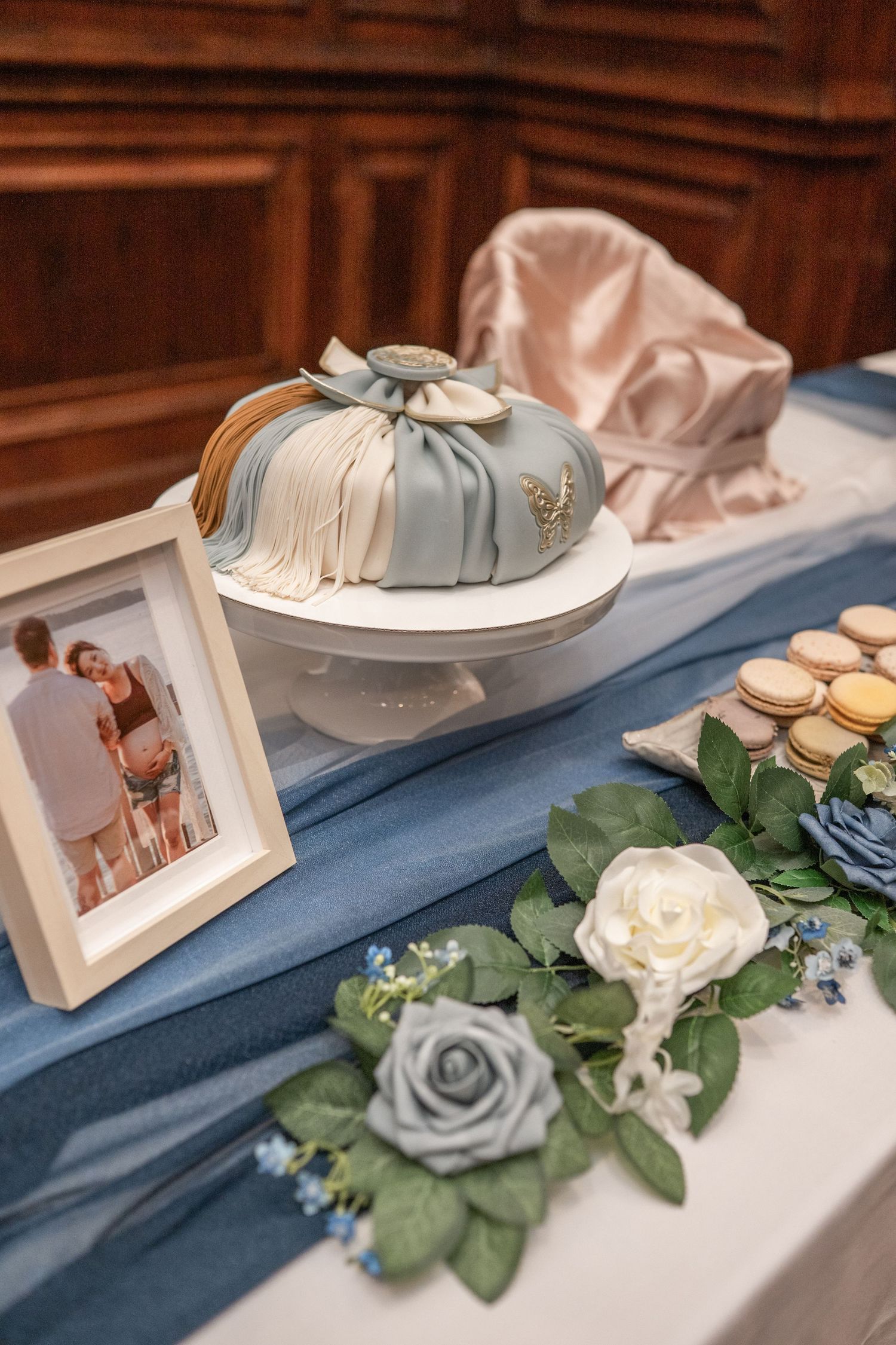Elegant table decor with blue fabric, white roses, and photo frames creating a formal display setting.