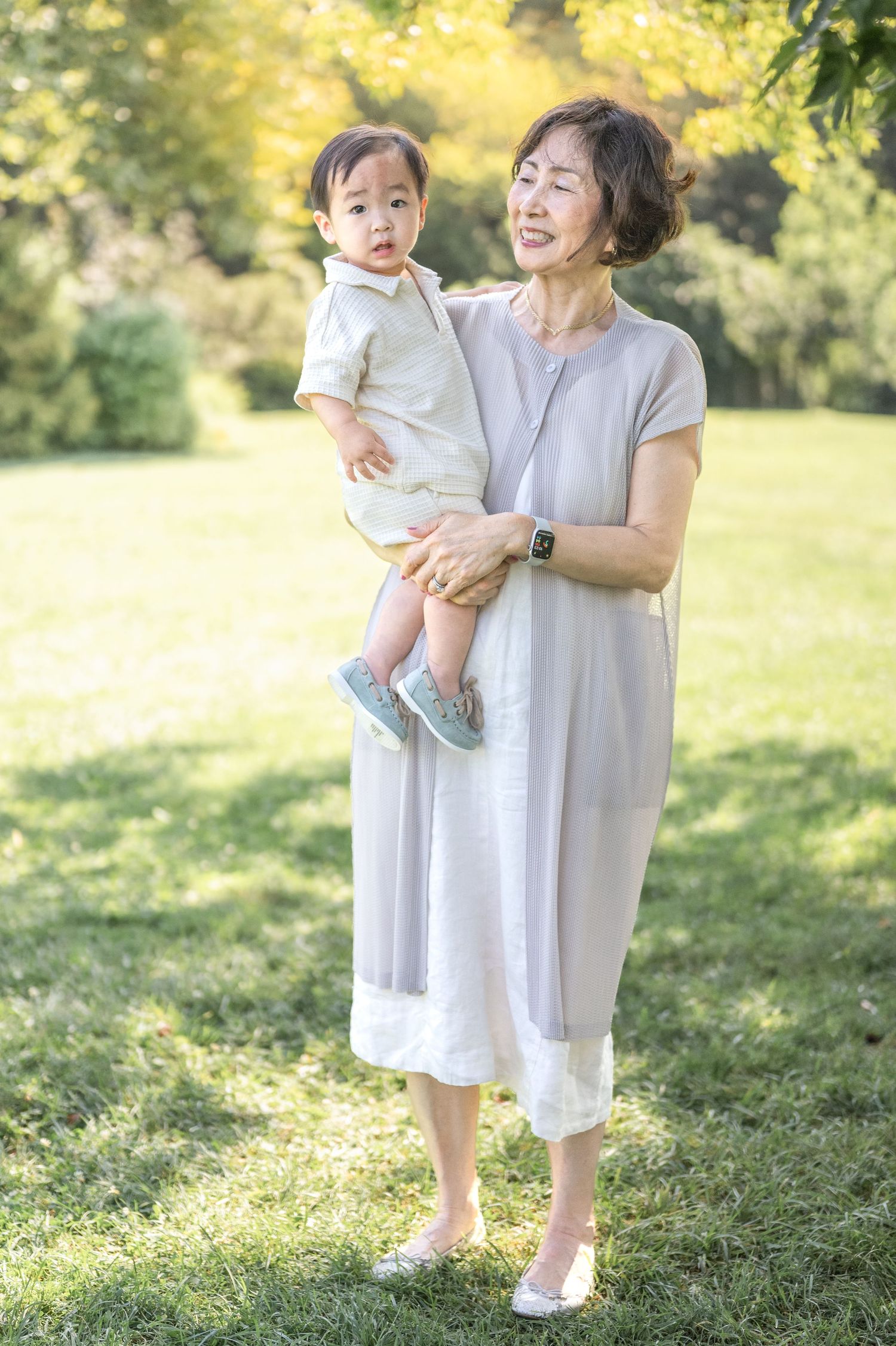A tender moment captured in a sunlit garden with light wash clothing and warm summer ambiance.