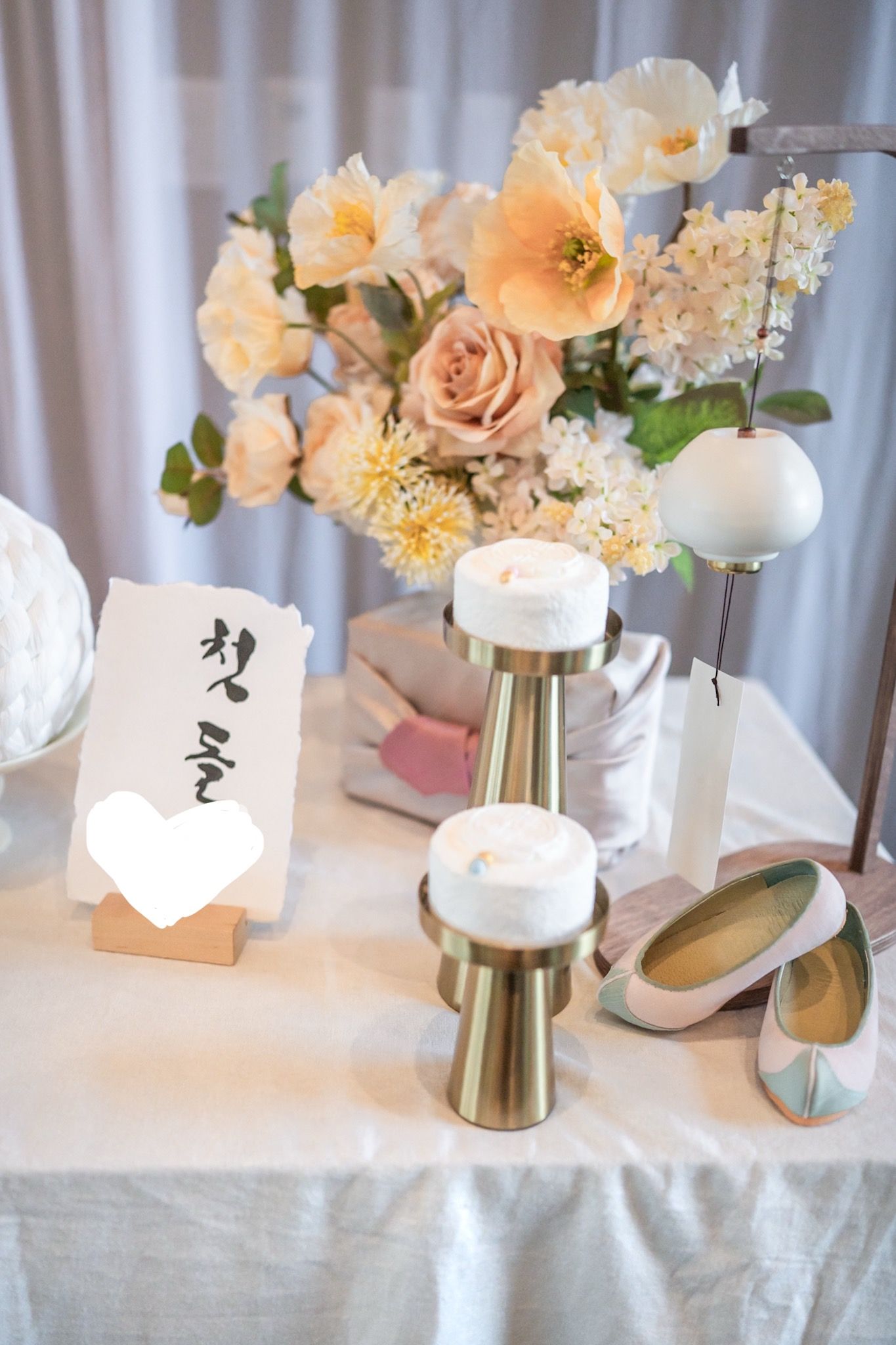 Elegant dohl table setting with peach and cream flowers in gold vases alongside white candles and place cards. Mclean photographer