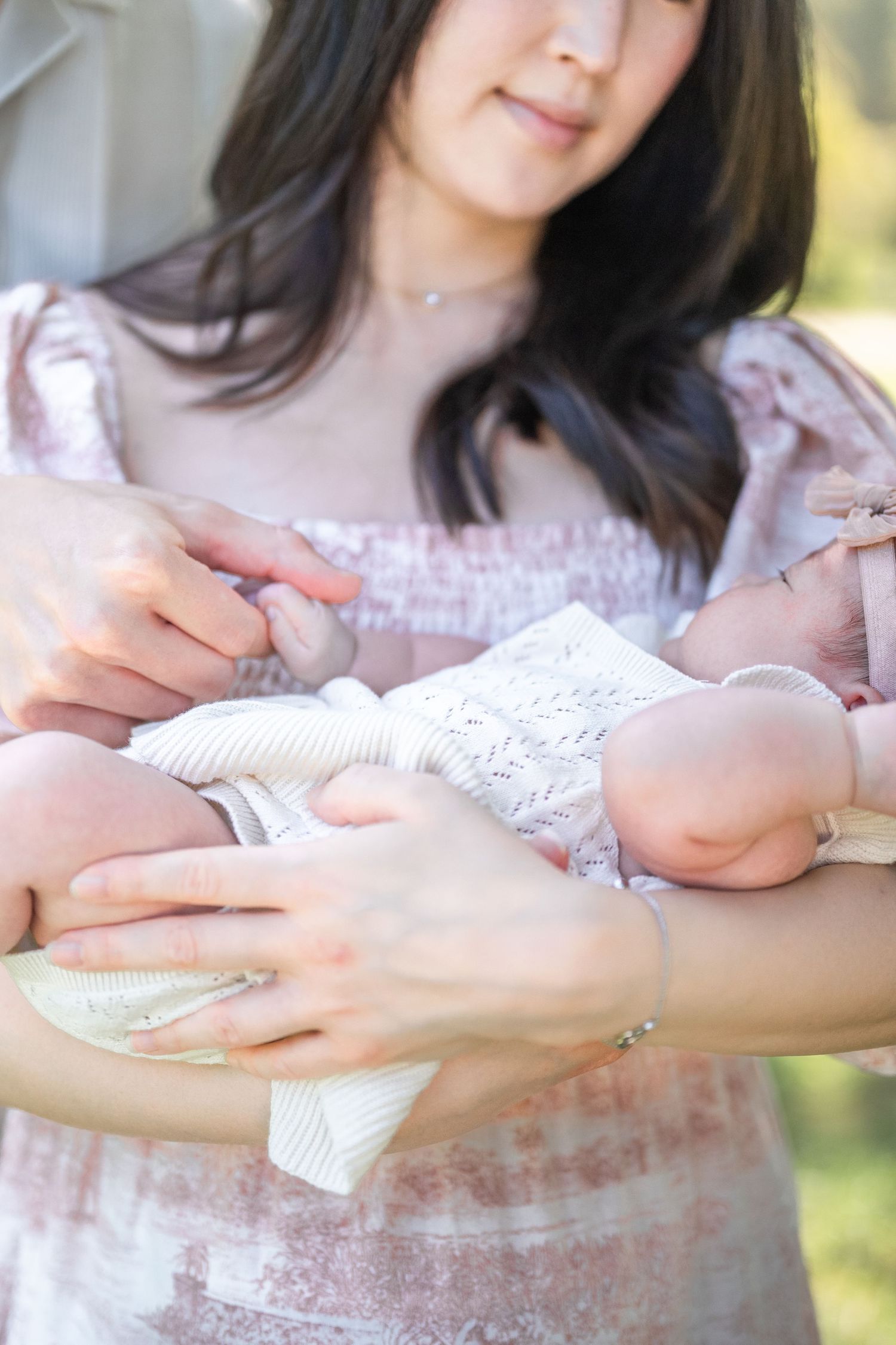 Hand wearing multiple delicate rings in a sunlit garden setting, shown in a sequence of similar detail shots. Photographer