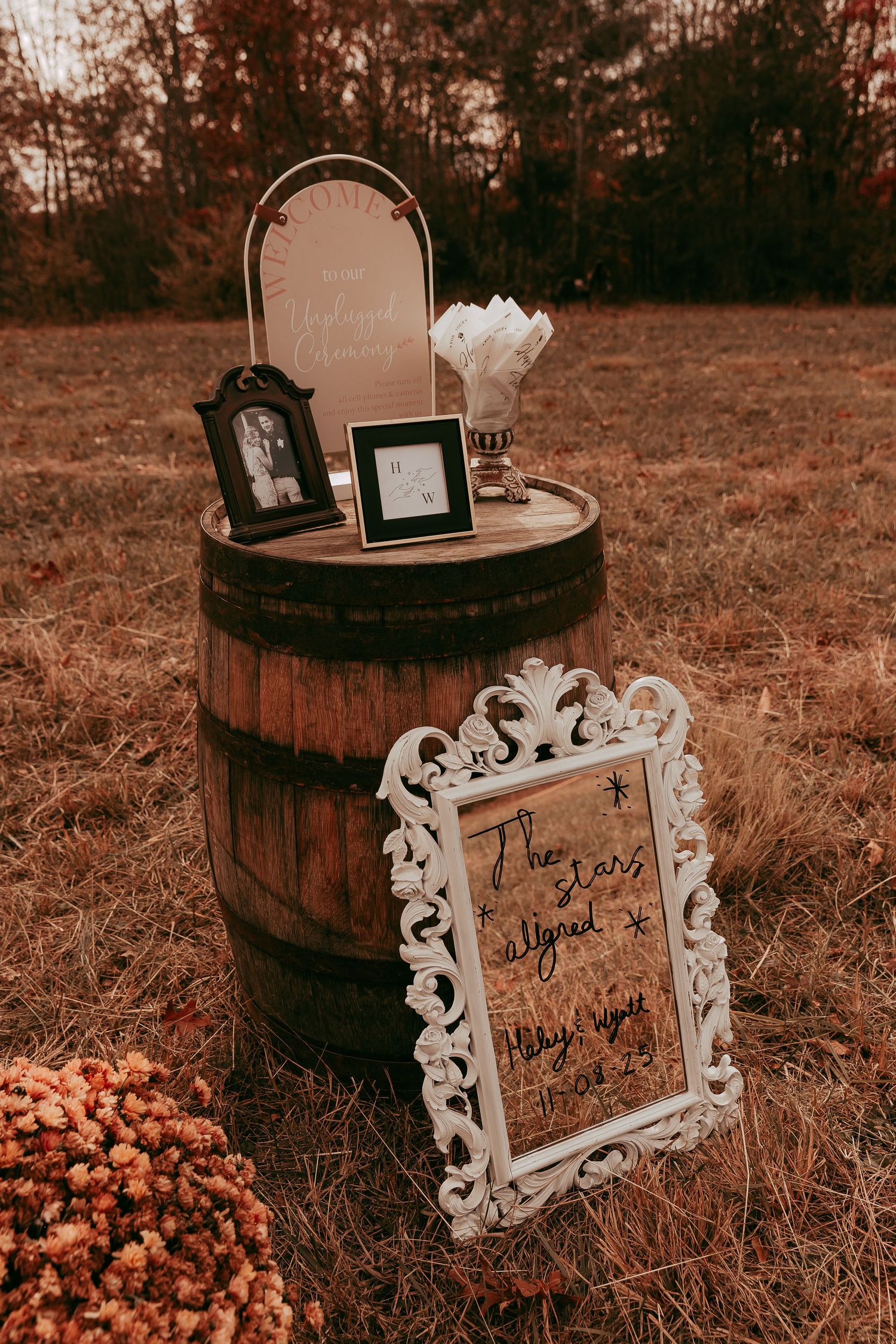 Rustic wooden barrel wedding display with vintage frames and ornate white mirror sign reading The Stars Aligned outdoors in autumn.
