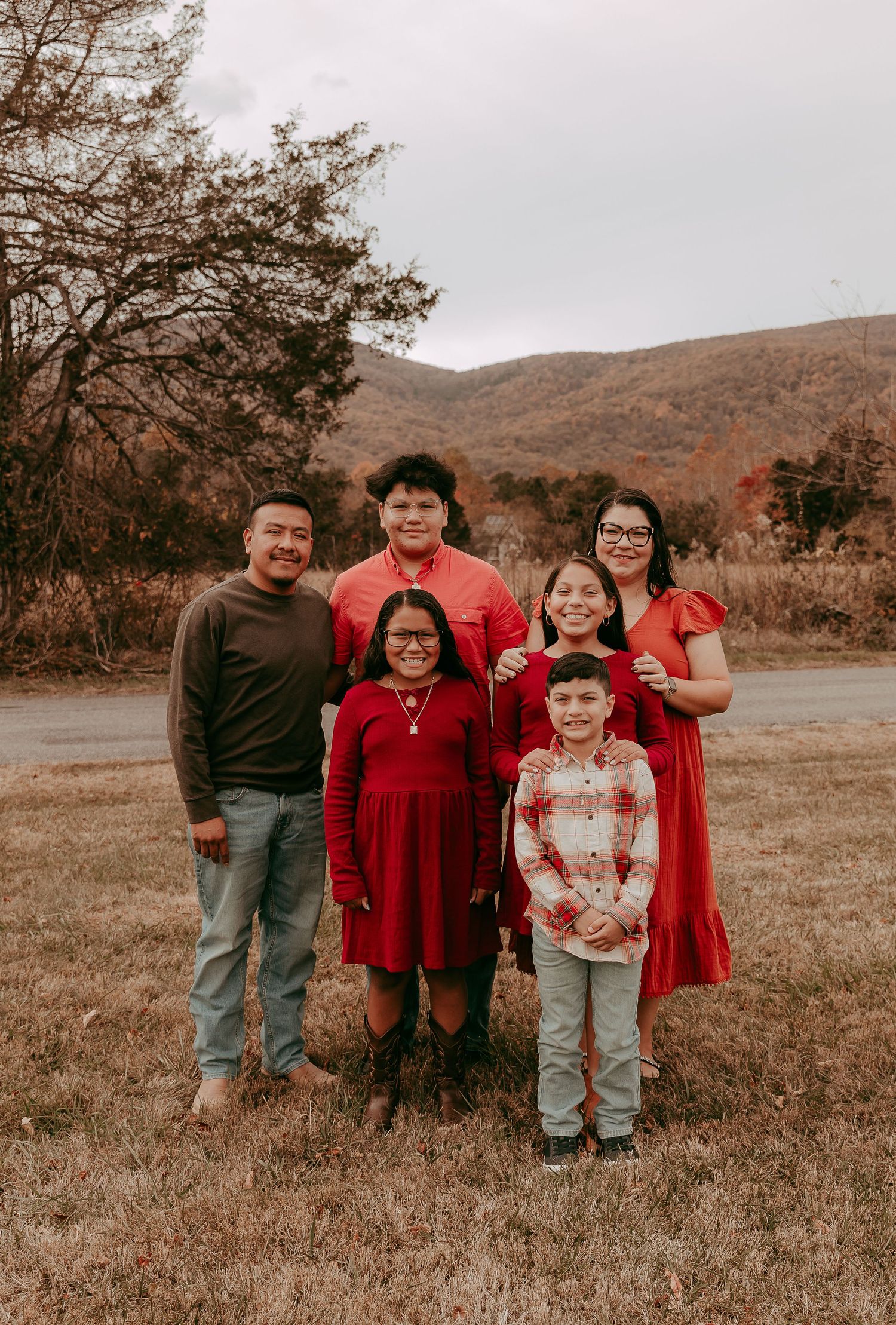 Family of six posing together in a field with stunning autumn mountain backdrop.