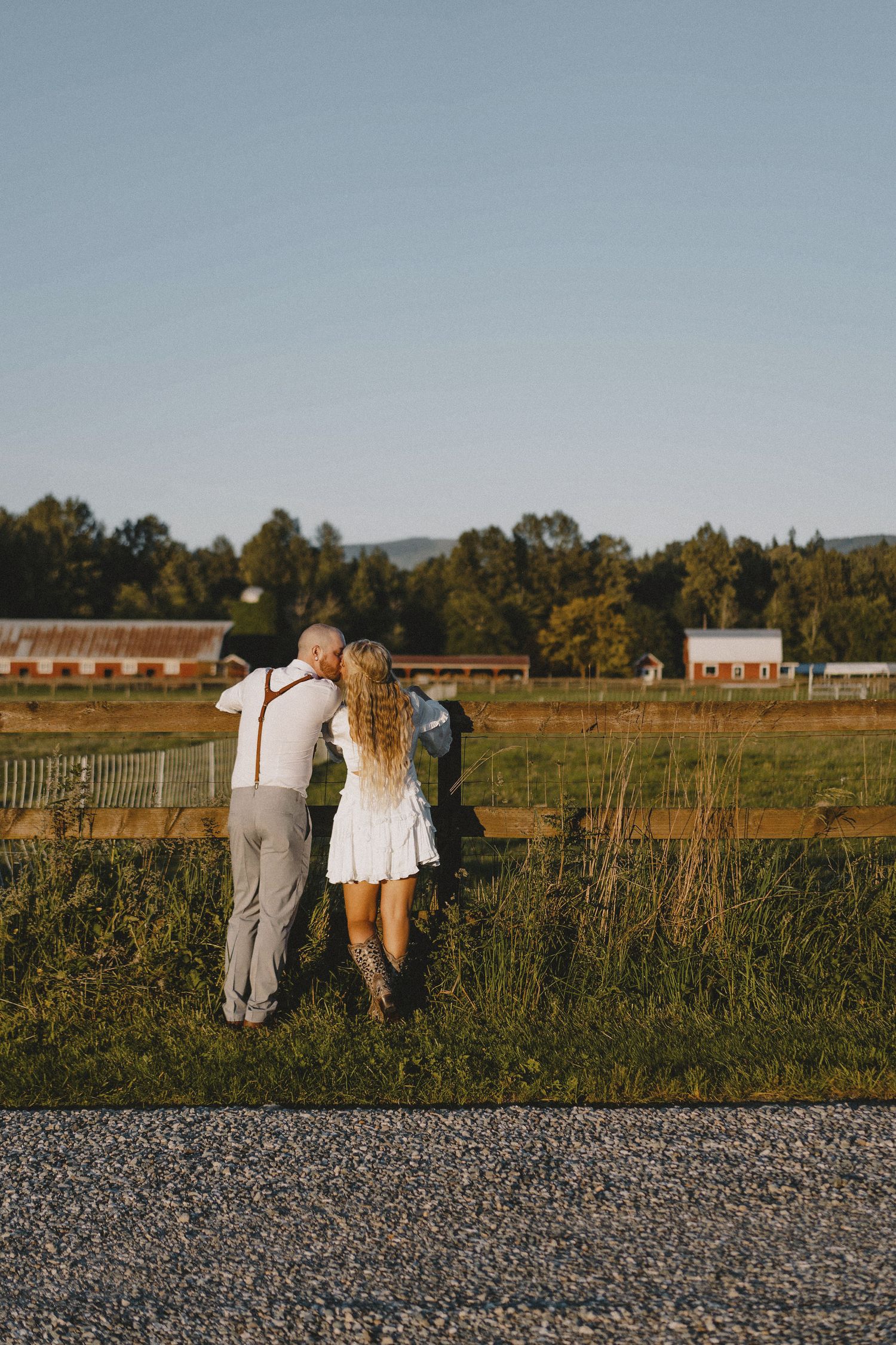 Bride and groom in field with expansive landscape view at sunset, cinematic editorial portrait at rustic Seattle destination wedding venue