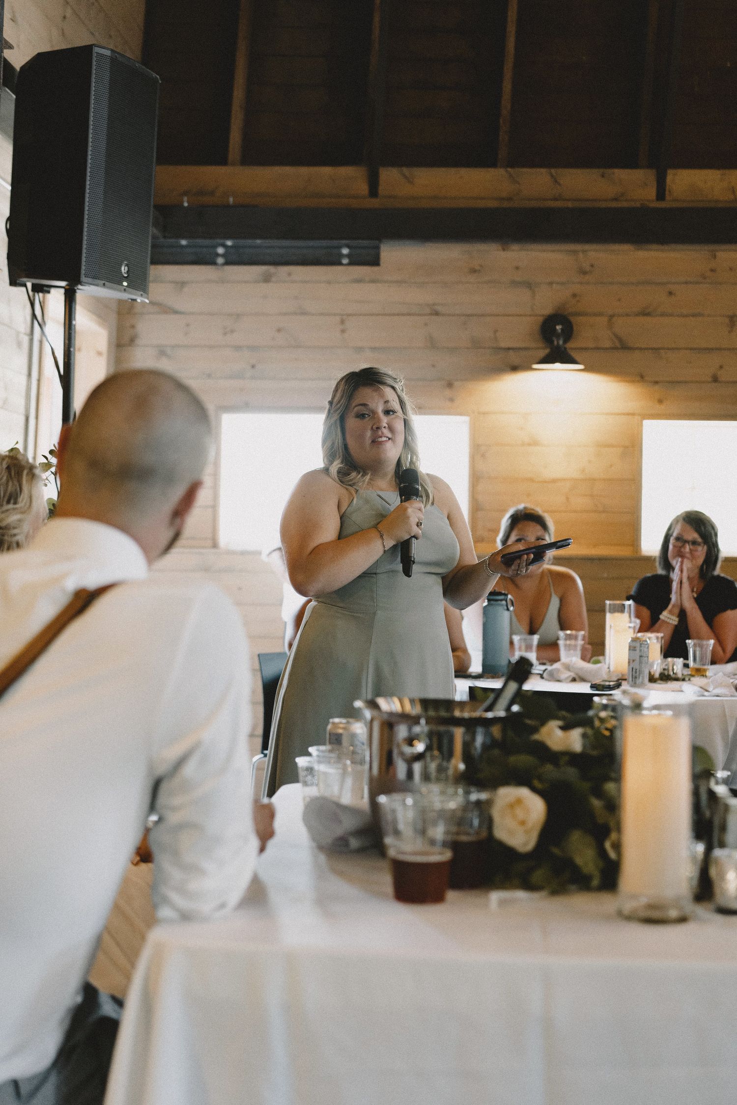 Bridesmaid speech at rustic Seattle reception, cinematic documentary photography capturing authentic guest reactions