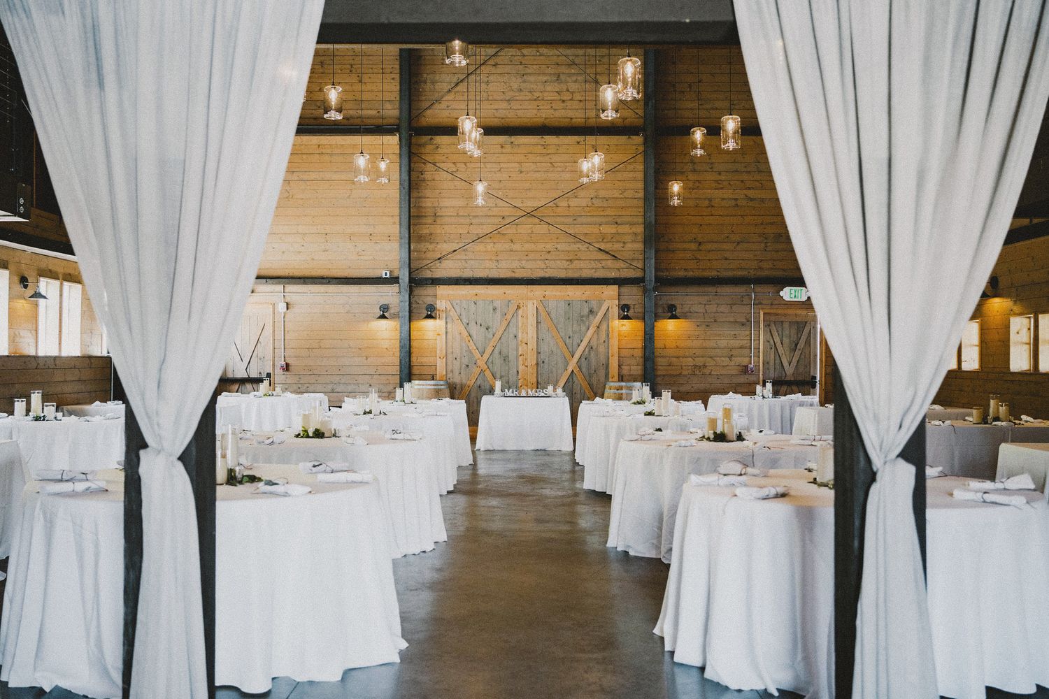 Elegant indoor reception setup at Seattle venue with white linens and drapery, cinematic documentary style with ambient lighting