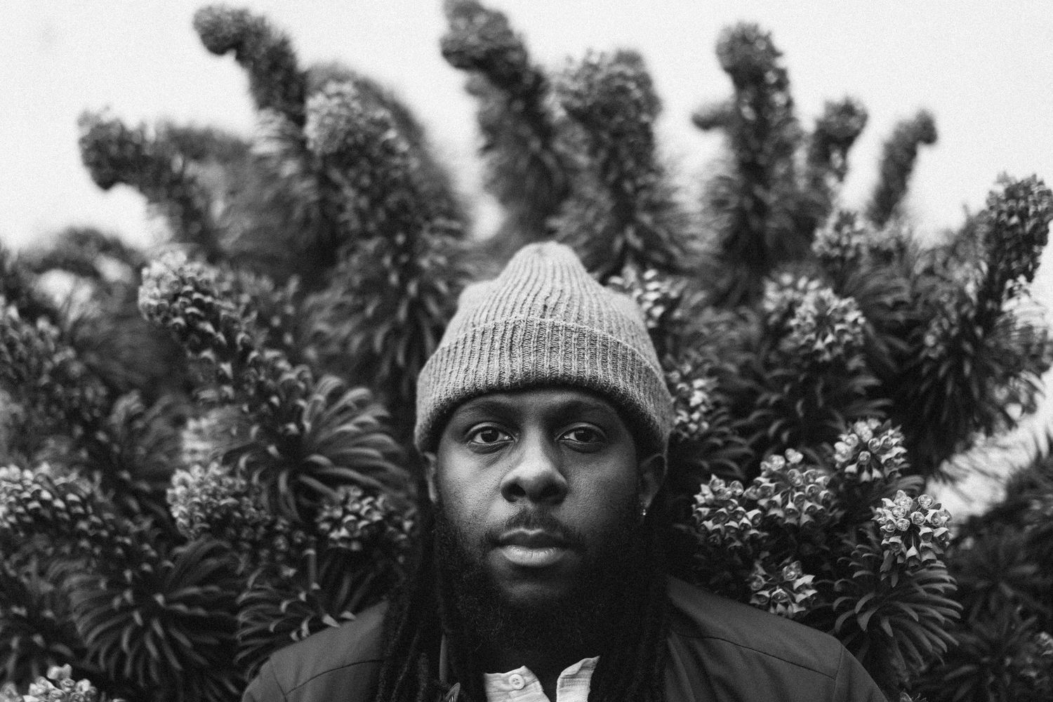 Black and white outdoor portrait with floral backdrop, Seattle 35mm film photography with moody cinematic approach