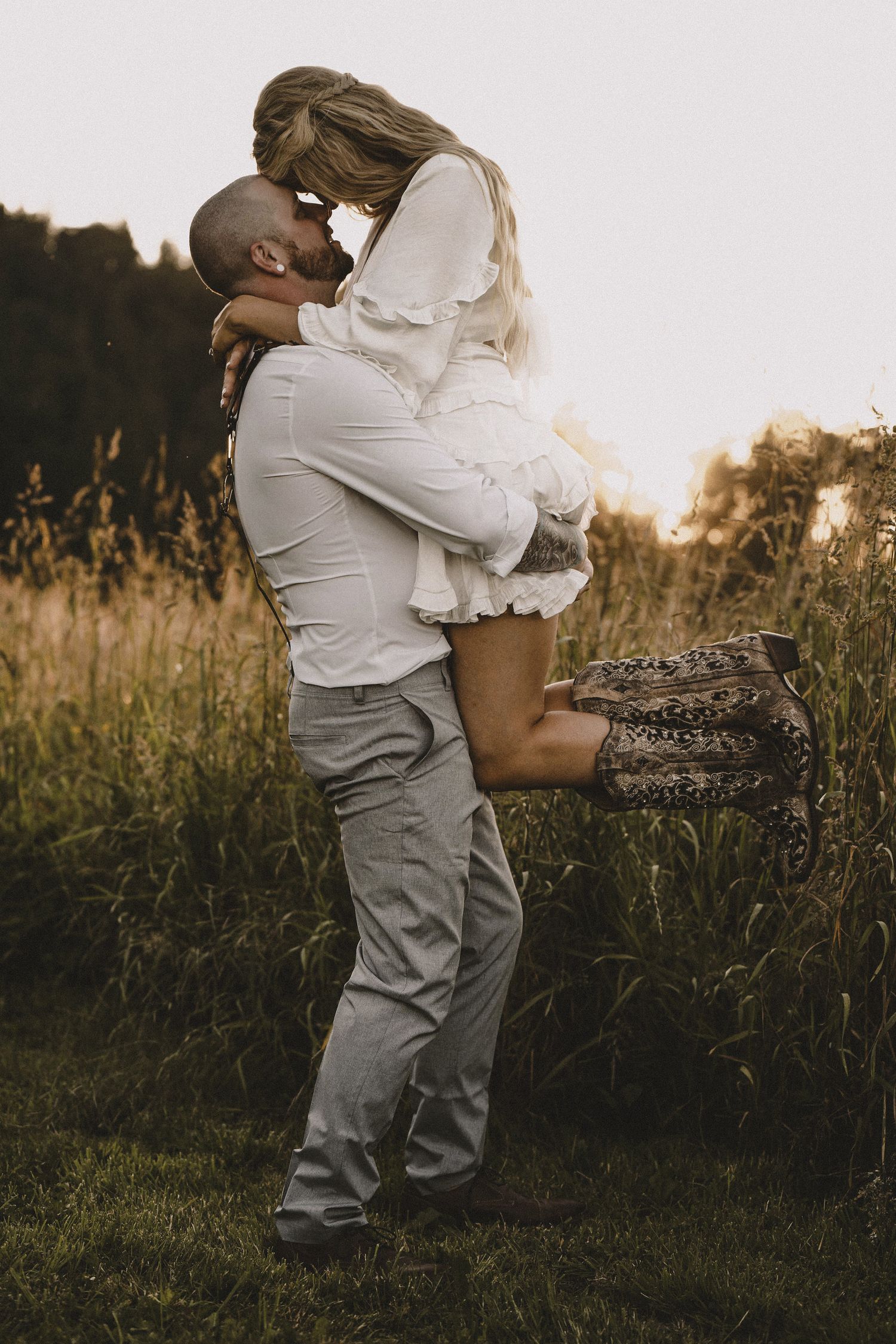 Golden hour couple portrait with groom lifting bride, cinematic rustic wedding photography with warm natural lighting