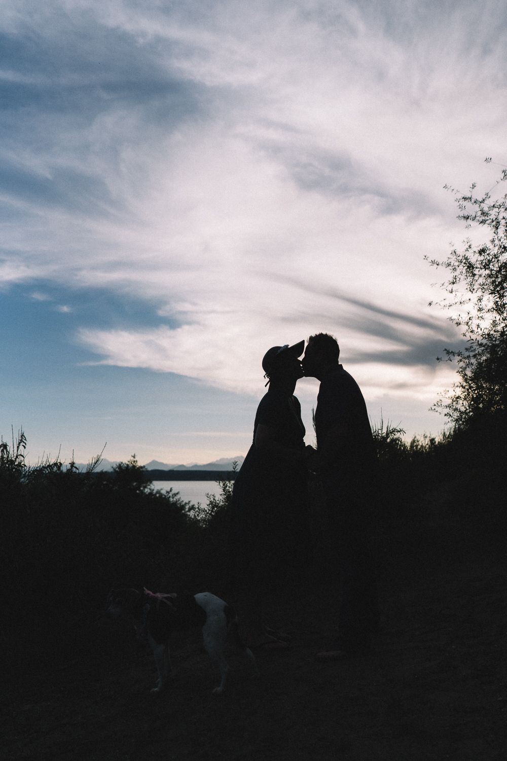 Silhouette of couple at sunset on Richmond Beach in Seattle, engagement photography with dramatic sky backdrop
