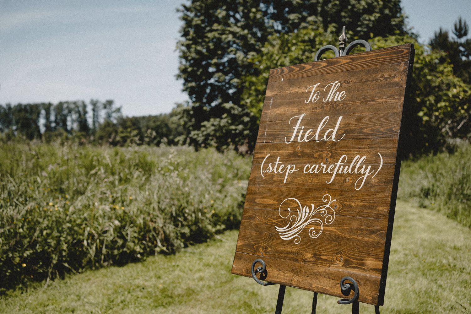 Rustic wooden welcome sign at outdoor Seattle wedding venue, cinematic photography with natural light and garden setting