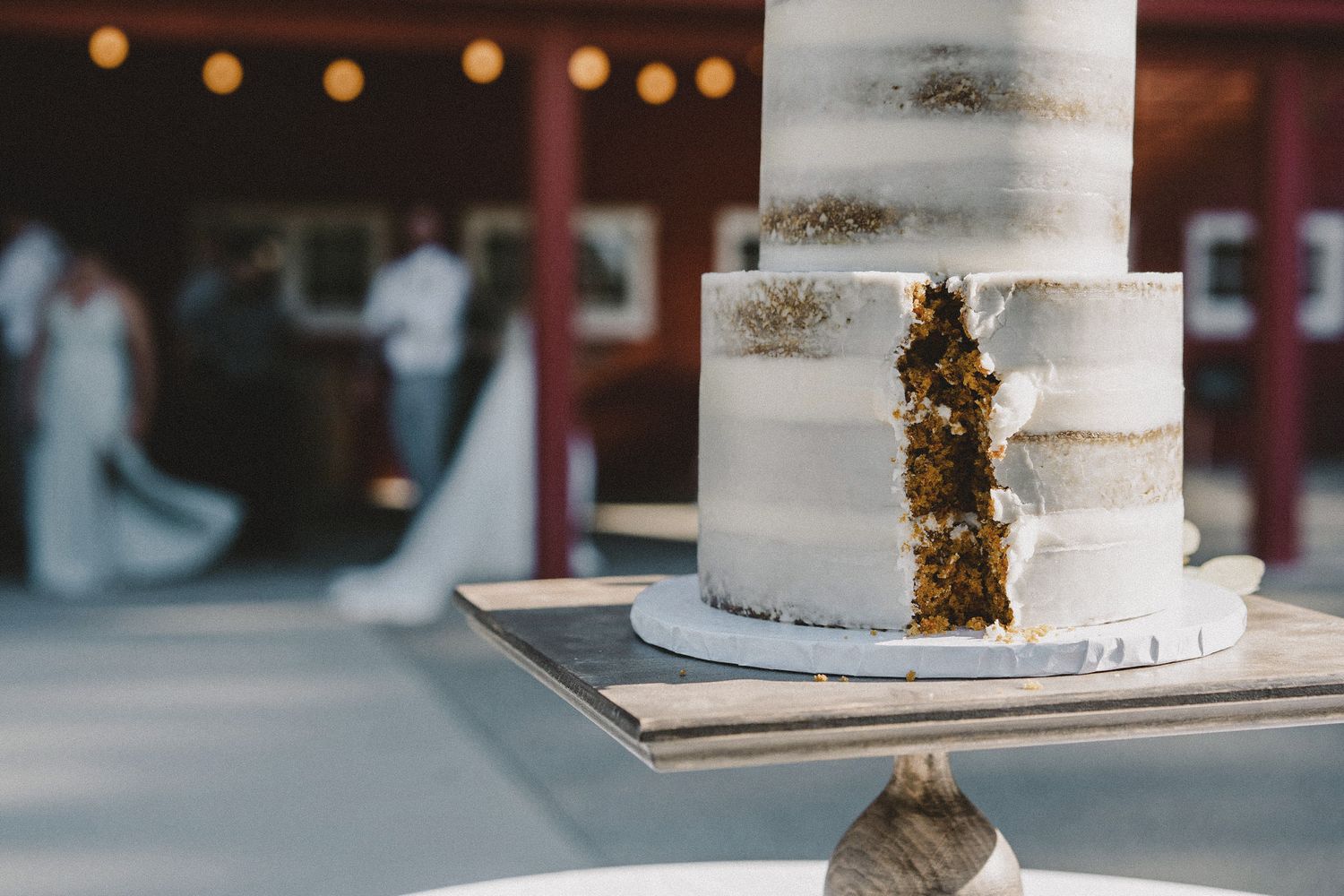 Elegant white wedding cake with gold accents at Seattle rustic venue, cinematic wedding detail photography with warm ambient lighting