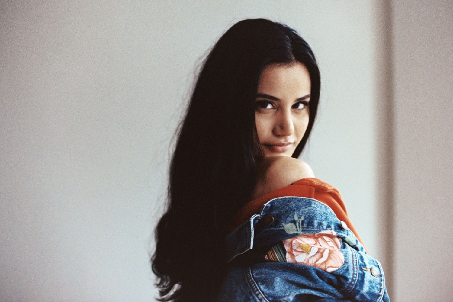 Soft window light portrait on 35mm film with off-shoulder jean jacket, Seattle studio photography with cinematic fashion approach