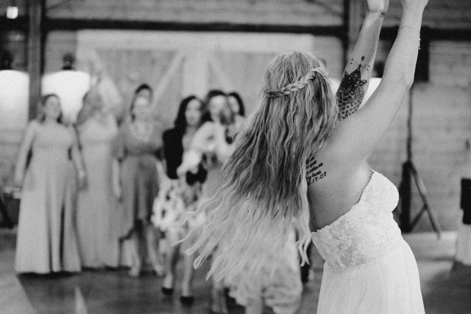 Cinematic black and white wedding party portrait in Seattle, showing stylish bridesmaids in editorial pose fighting for a bouquet