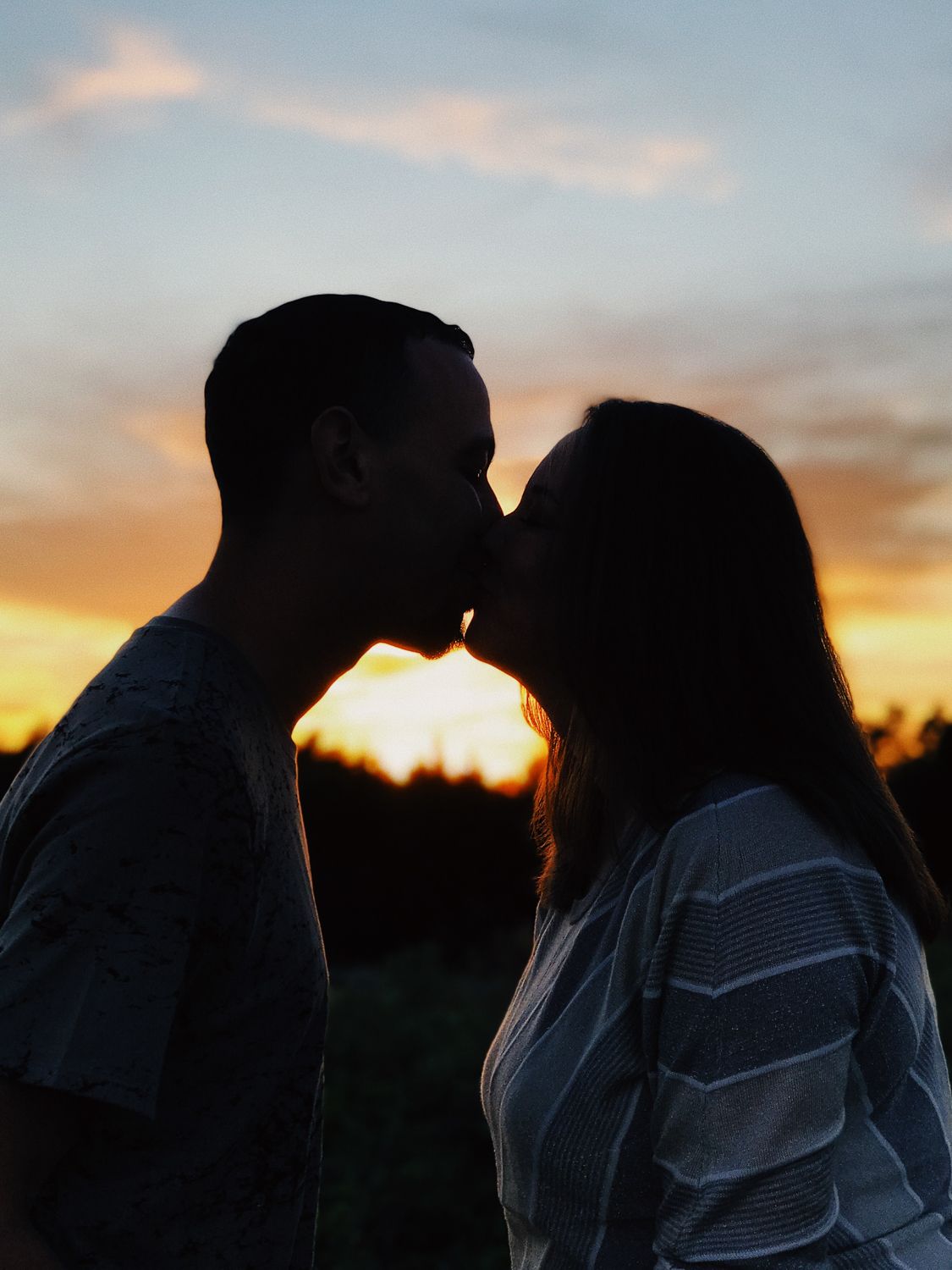 Sunset silhouette kiss portrait in Dallas, golden hour engagement photography with dramatic sky colors