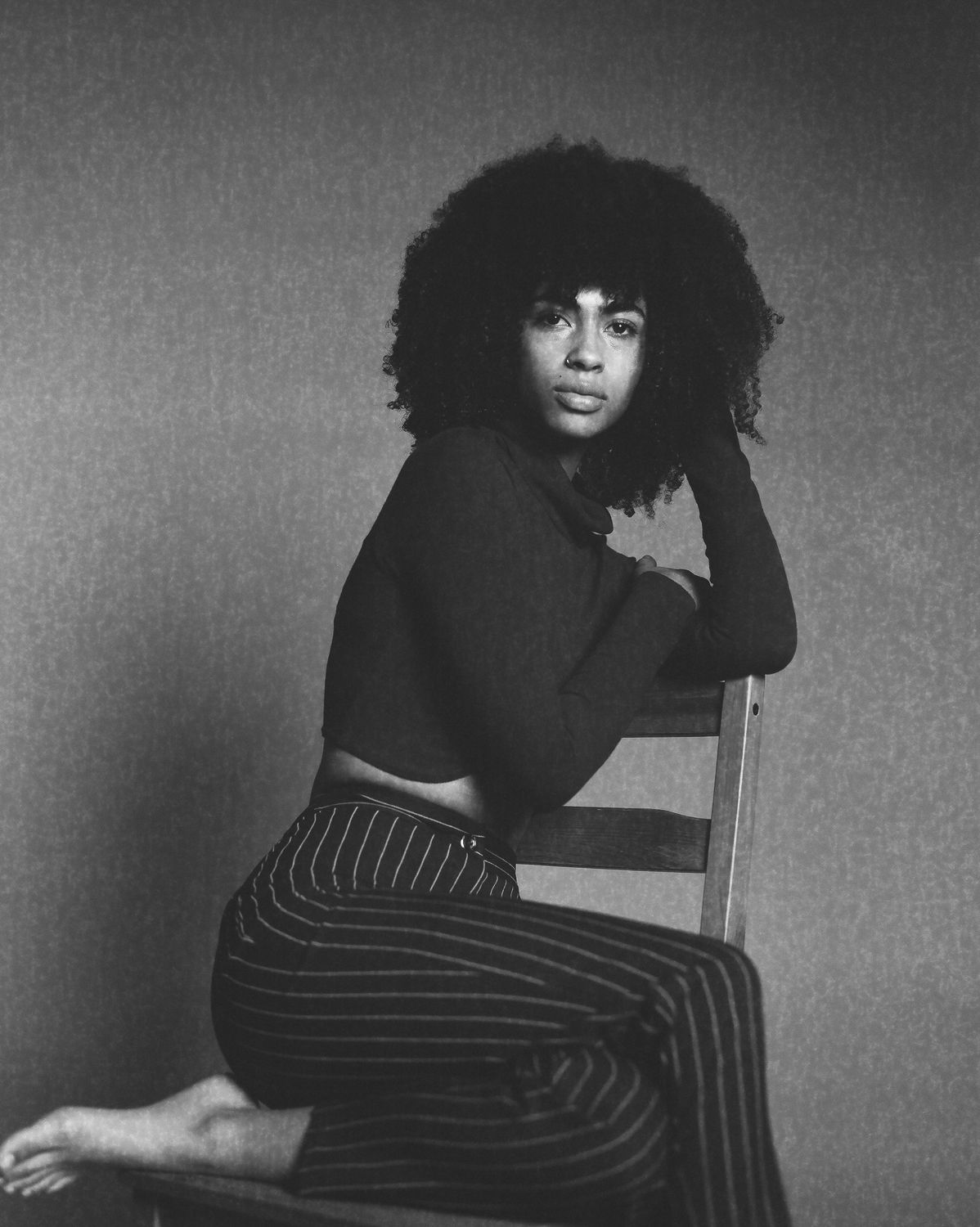 Black and white fashion portrait with curly hair and striped outfit, Seattle film photography with dramatic lighting and vintage styling