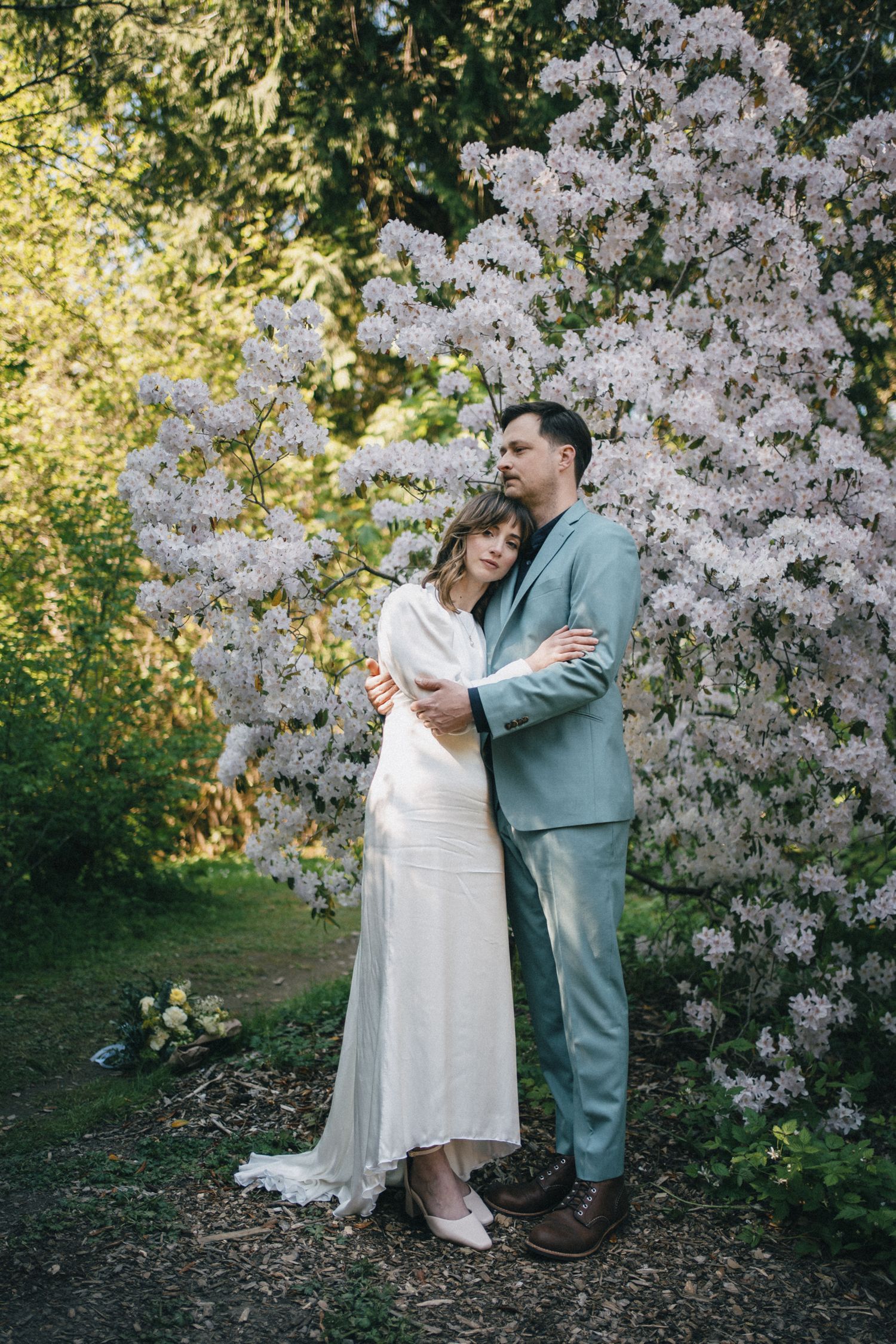 Seattle spring wedding portrait featuring couple embracing among blooming cherry blossoms, showcasing intimate documentary-style photography