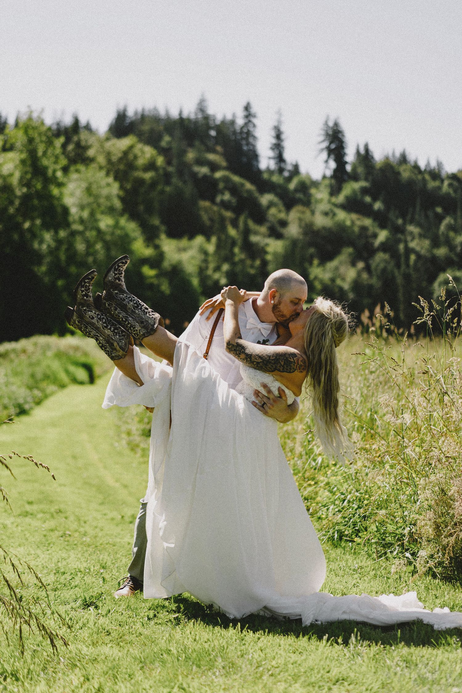 Bride carrying groom in sunny field with natural light, cinematic wedding photography at outdoor Seattle venue with lush greenery