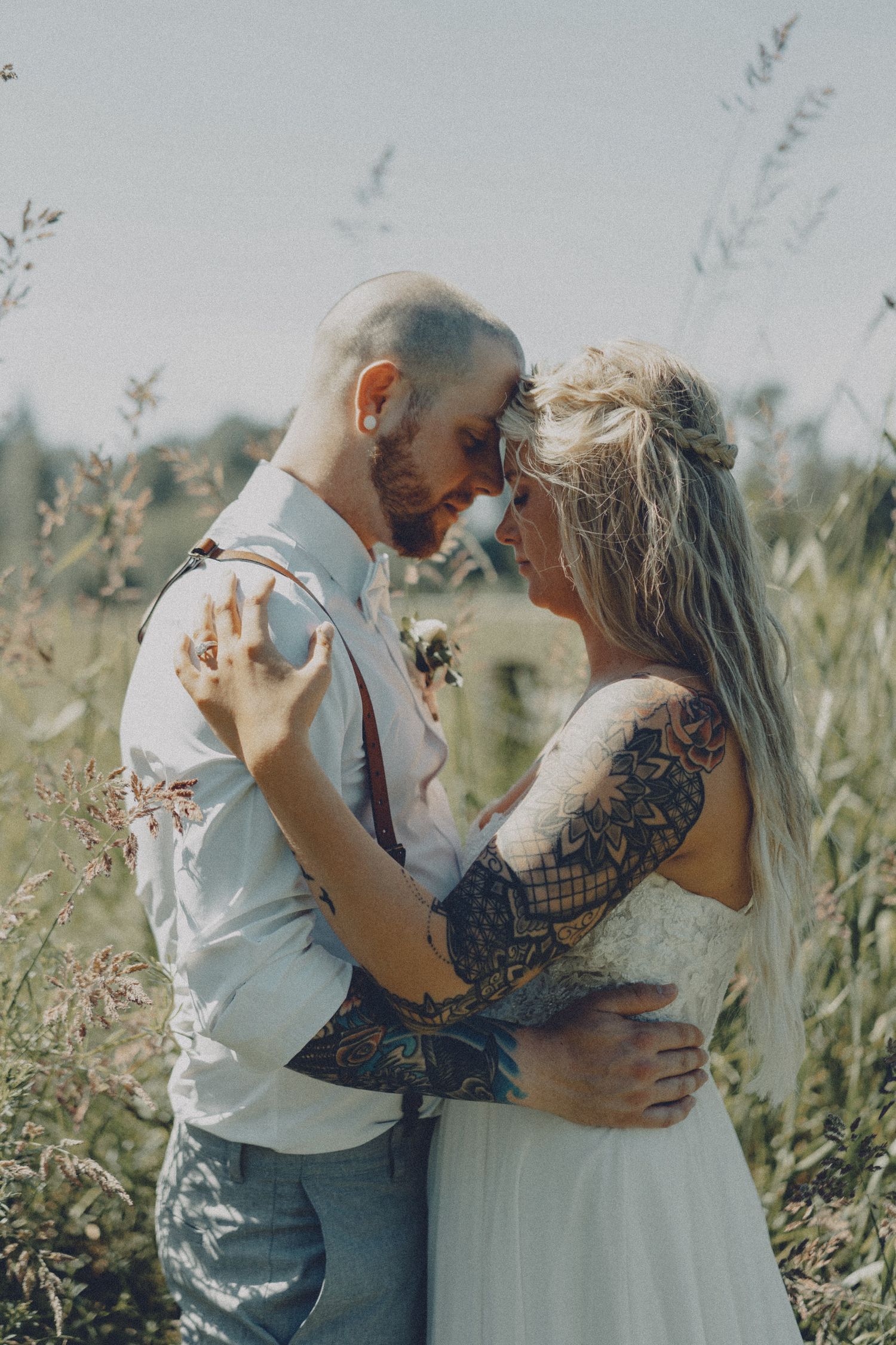 Intimate couple portrait in field with soft natural light, cinematic outdoor wedding photography with editorial approach