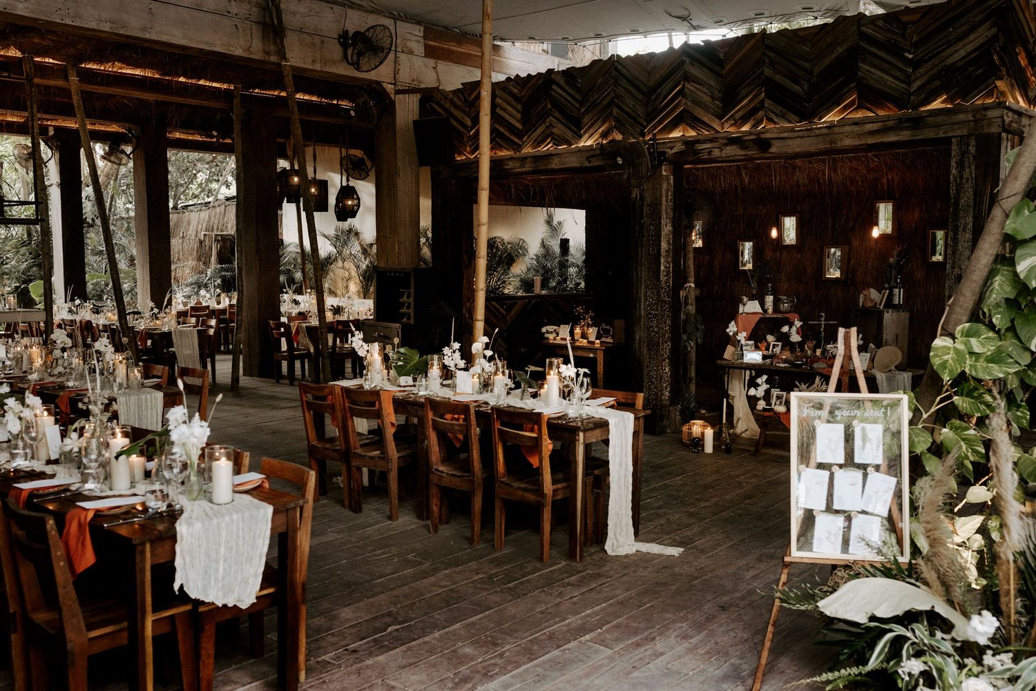 Bohemian luxury open-air Tulum wedding reception venue with wooden tables, natural surroundings, and elegant decor for destination ambiance