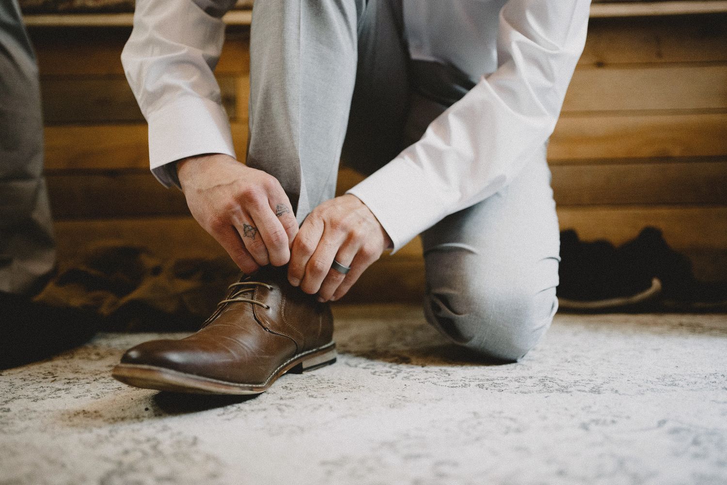 Groom tying leather dress shoes, intimate getting ready moment with cinematic documentary approach at rustic Seattle venue