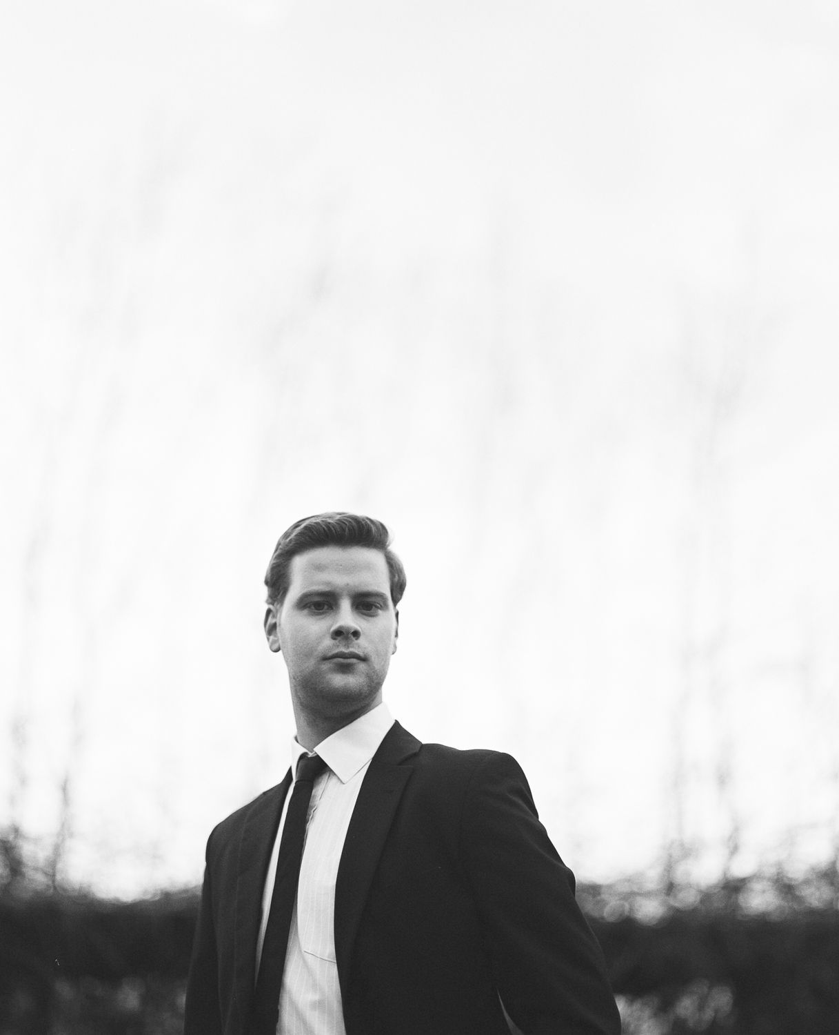 Black and white formal portrait of man in suit in Seoul, cinematic film photography with dramatic contrast and foggy backdrop
