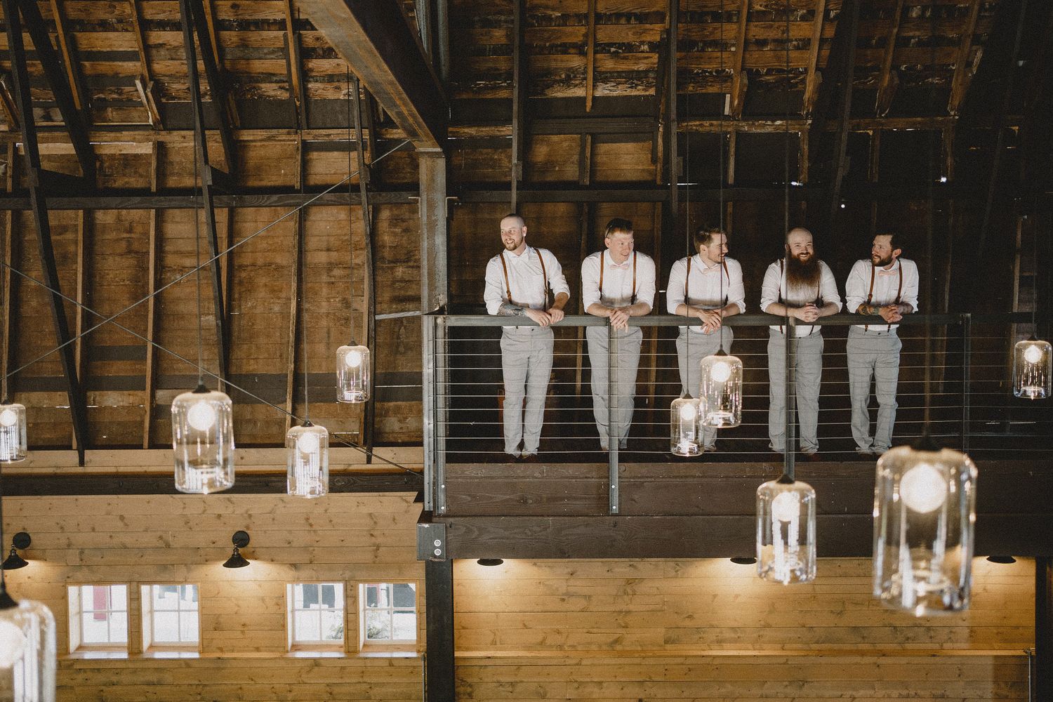Groomsmen in formal attire standing in rustic barn wedding venue in Seattle, cinematic composition with warm lighting