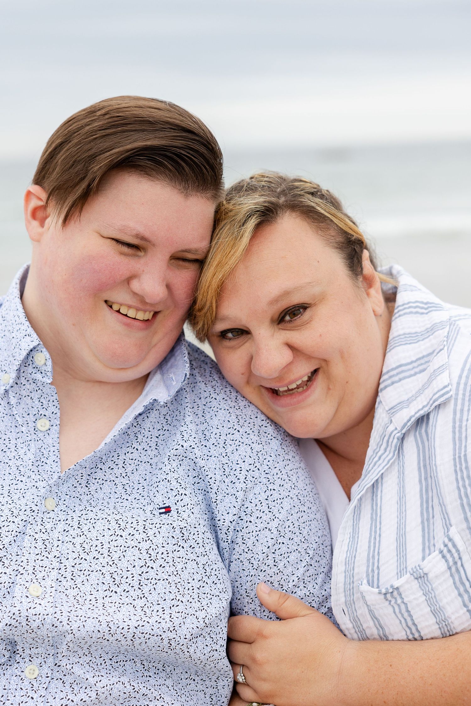 Two people sharing a joyful moment together outdoors with a cloudy sky in the background.