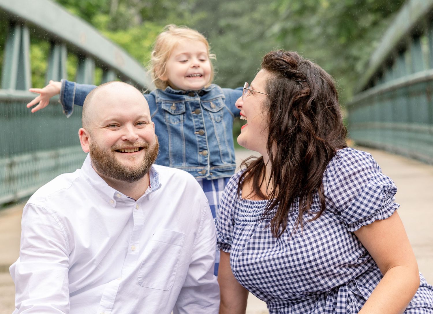 Candid family moment captured on bridge with joyful expressions and casual attire.