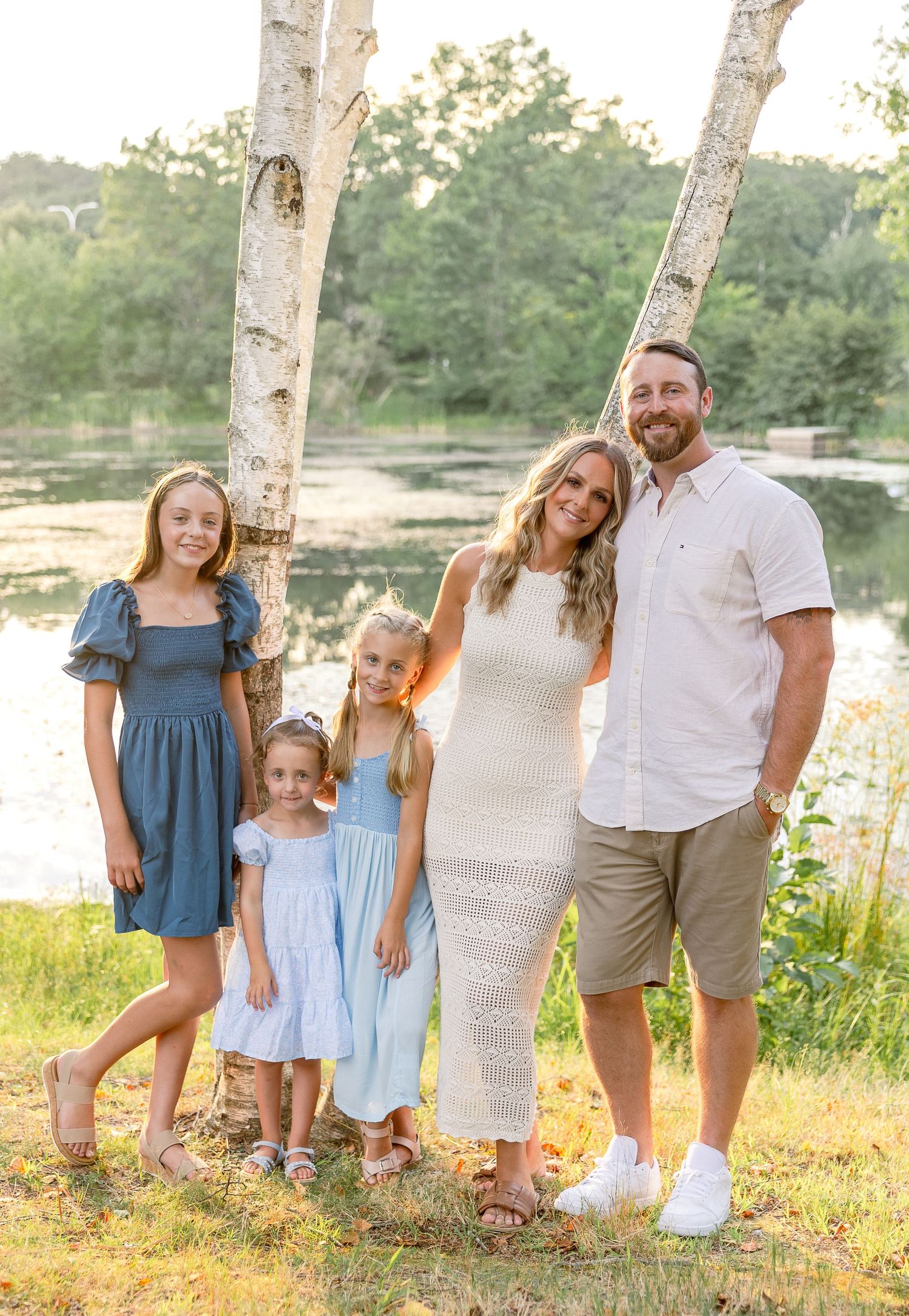 Family of five standing between birch trees for outdoor portrait in summer setting.