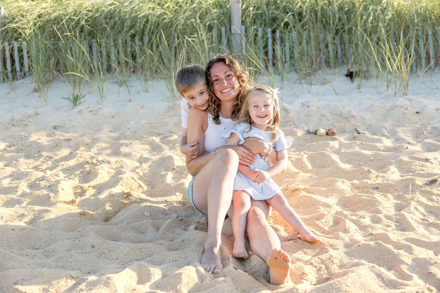 Candid family portrait with parents and children laughing together on sunny beach.