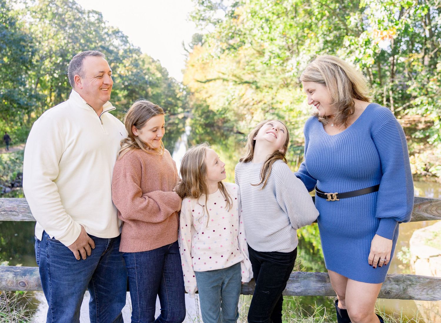 Happy family enjoying candid outdoor moment together in casual attire against natural backdrop.