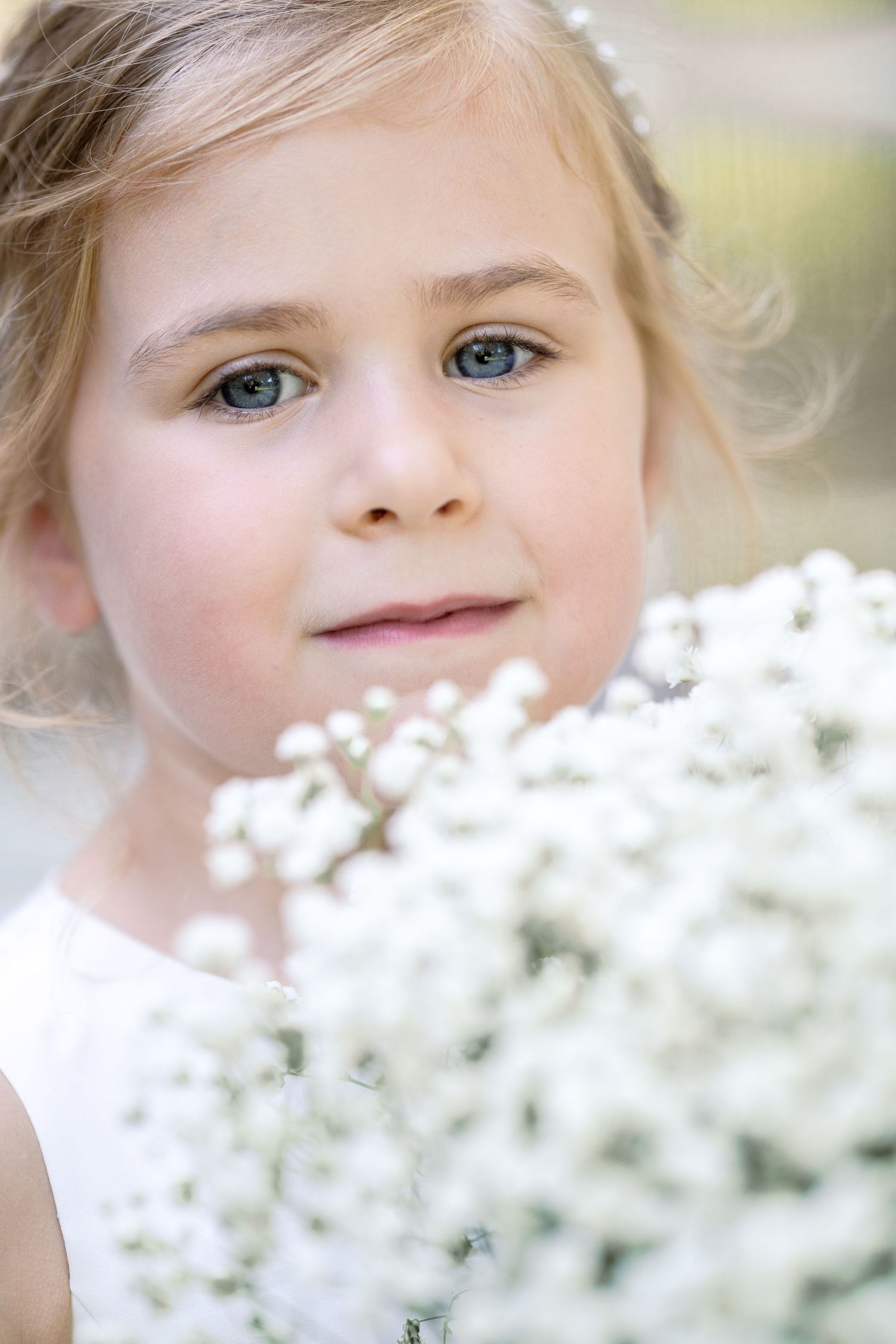 A portrait surrounded by delicate white flowers with soft bokeh effect and natural lighting in the background.