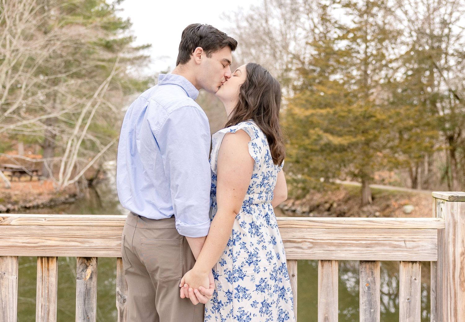 A romantic moment shared between two people in dressy casual attire on a wooden deck surrounded by autumn trees.