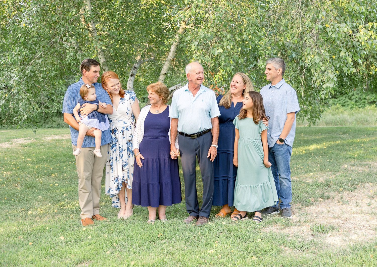 Multi-generational family group posing together outdoors in casual clothing.