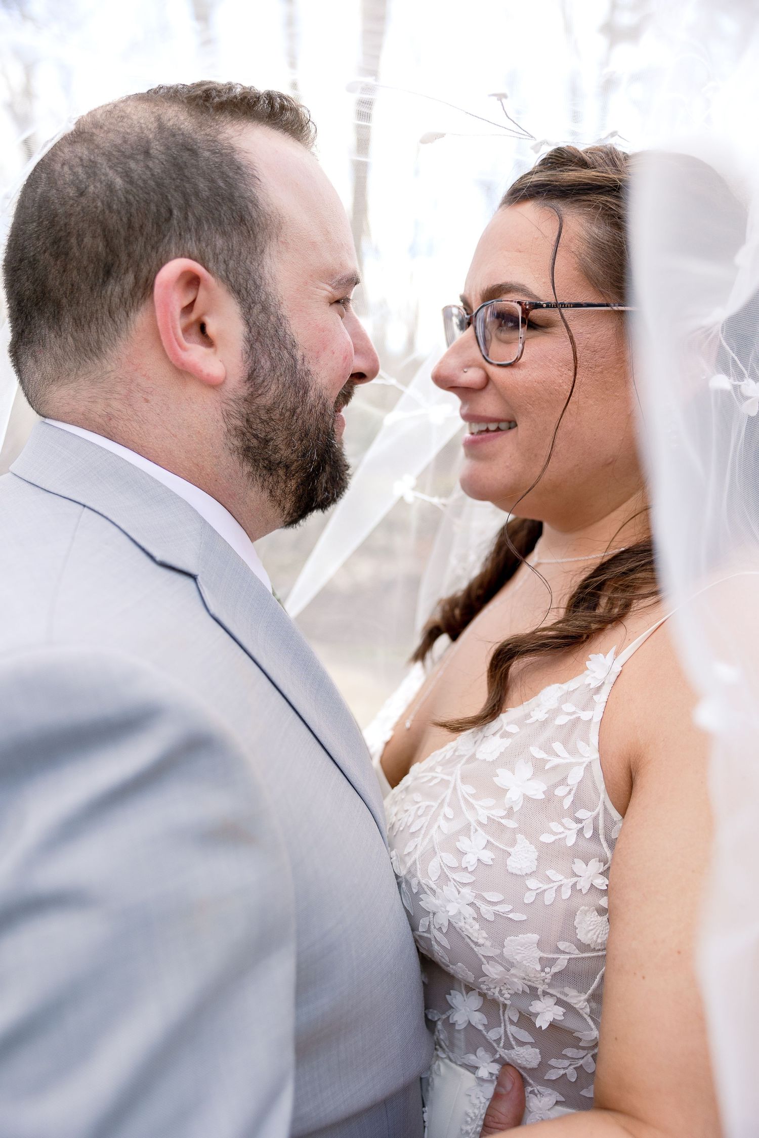 Close-up of newlyweds sharing an intimate moment with bride in lace dress.