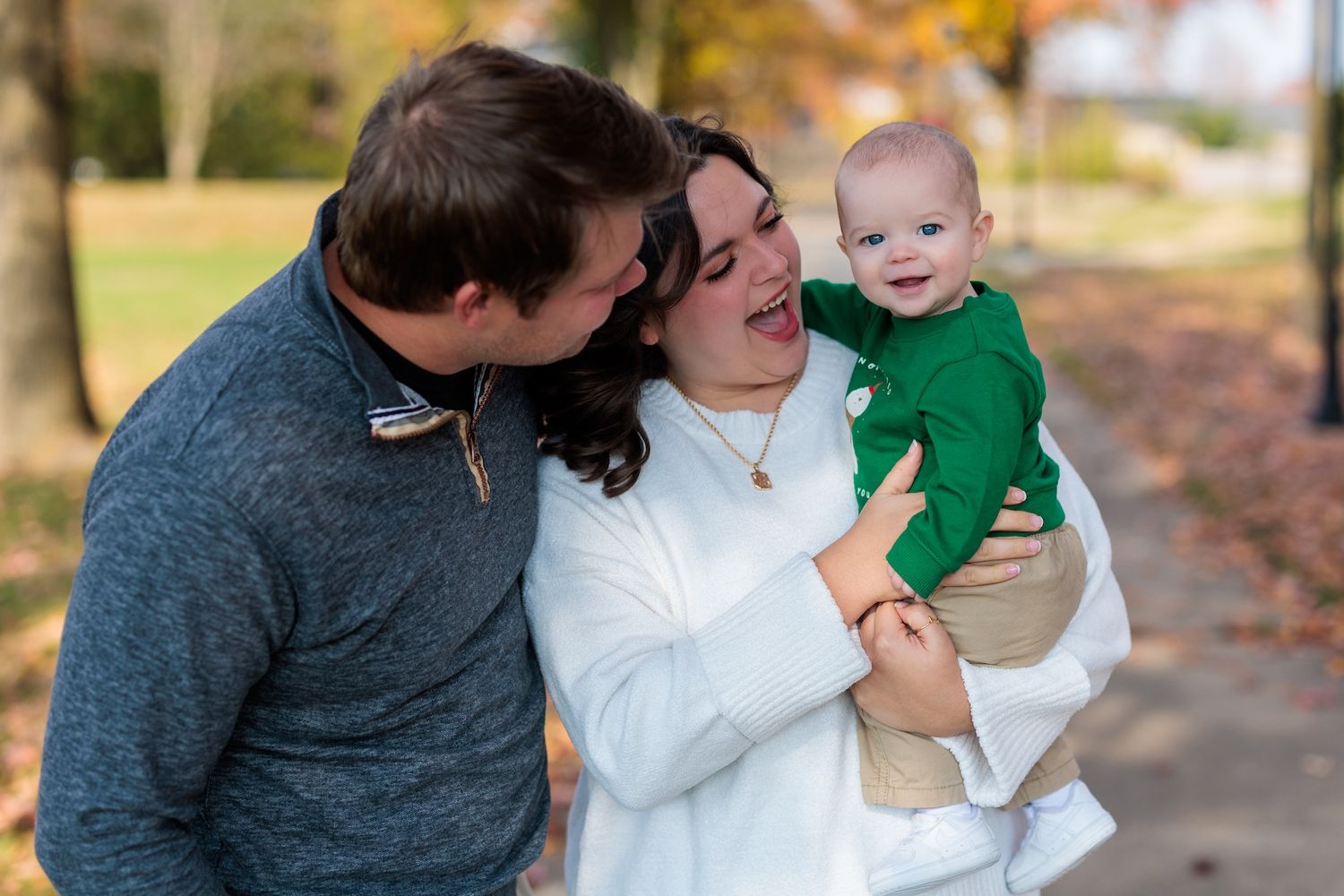 A family in cozy sweaters share a tender outdoor moment together on an autumn day.