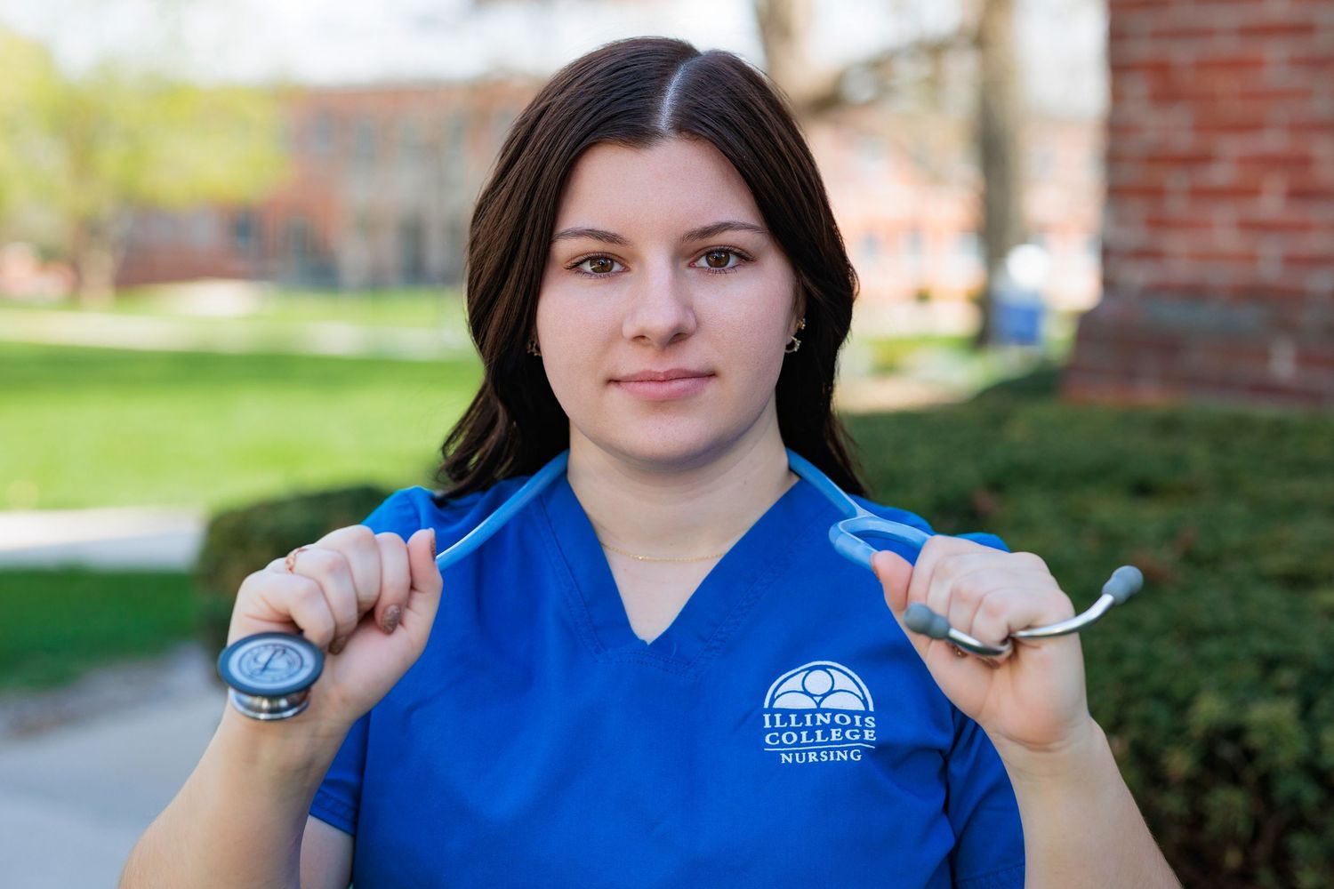 Student in bright blue Marauders uniform smiles while standing outdoors near a brick building.