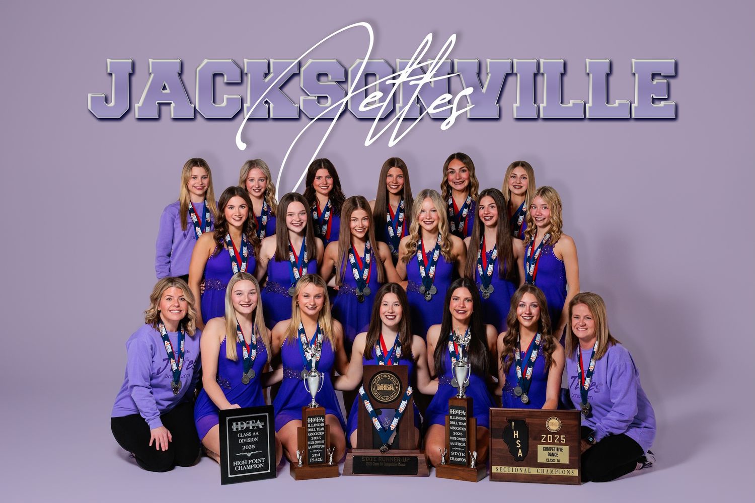 High school athletic team posing with trophies in purple team uniforms for official photo.
