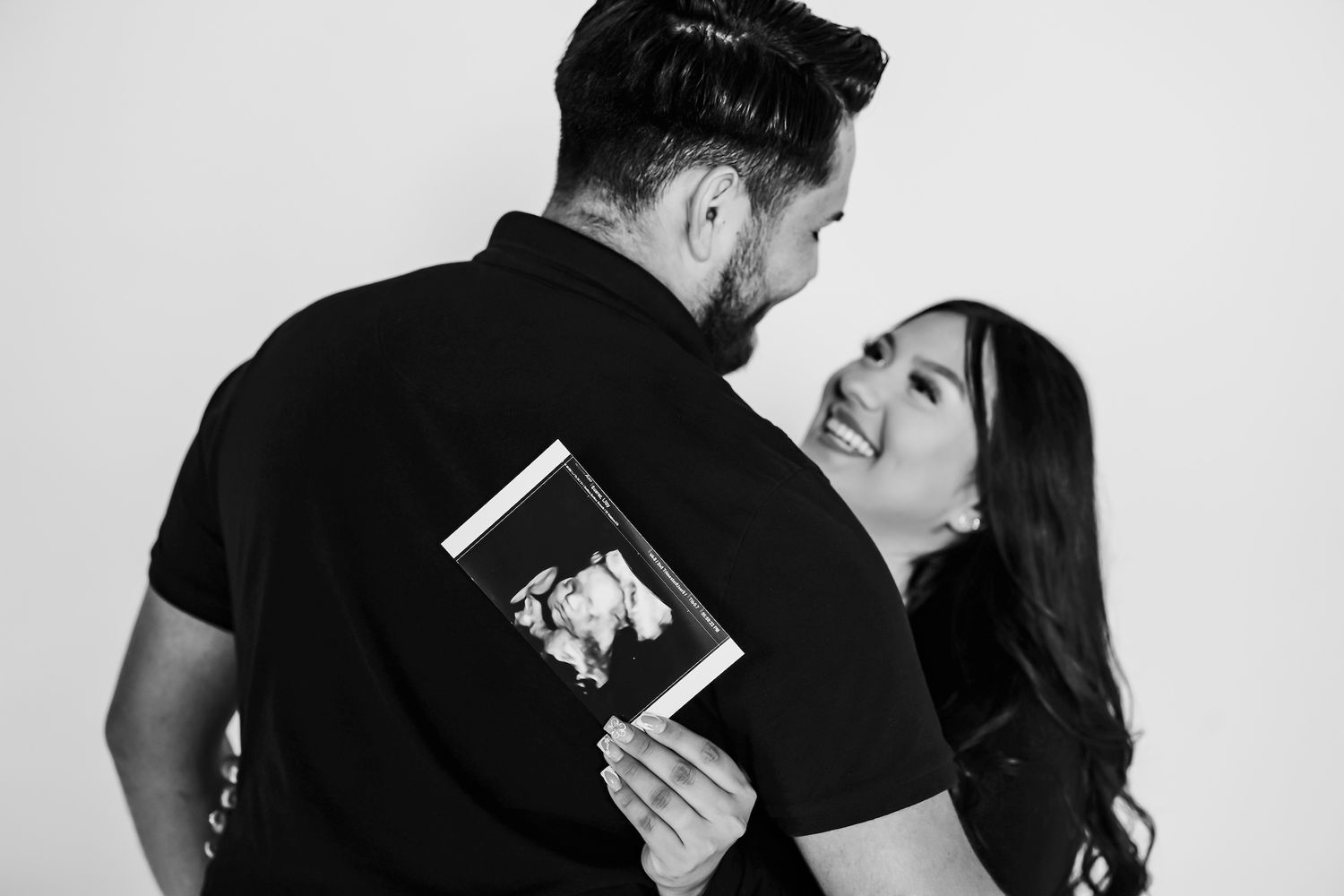 Black and white photo of couple holding a photo frame while sharing an intimate romantic moment.